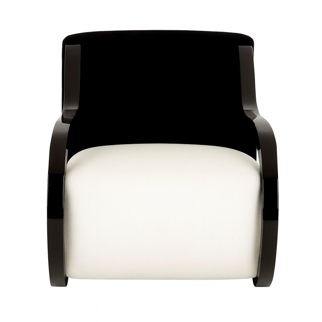 Una poltrona scultorea caratterizzata da un'audace silhouette architettonica con braccioli a voluta in lacca nera lucida. Lo schienale è rivestito in ricco velluto nero, per creare profondità e drammaticità, mentre la seduta è rifinita in tessuto