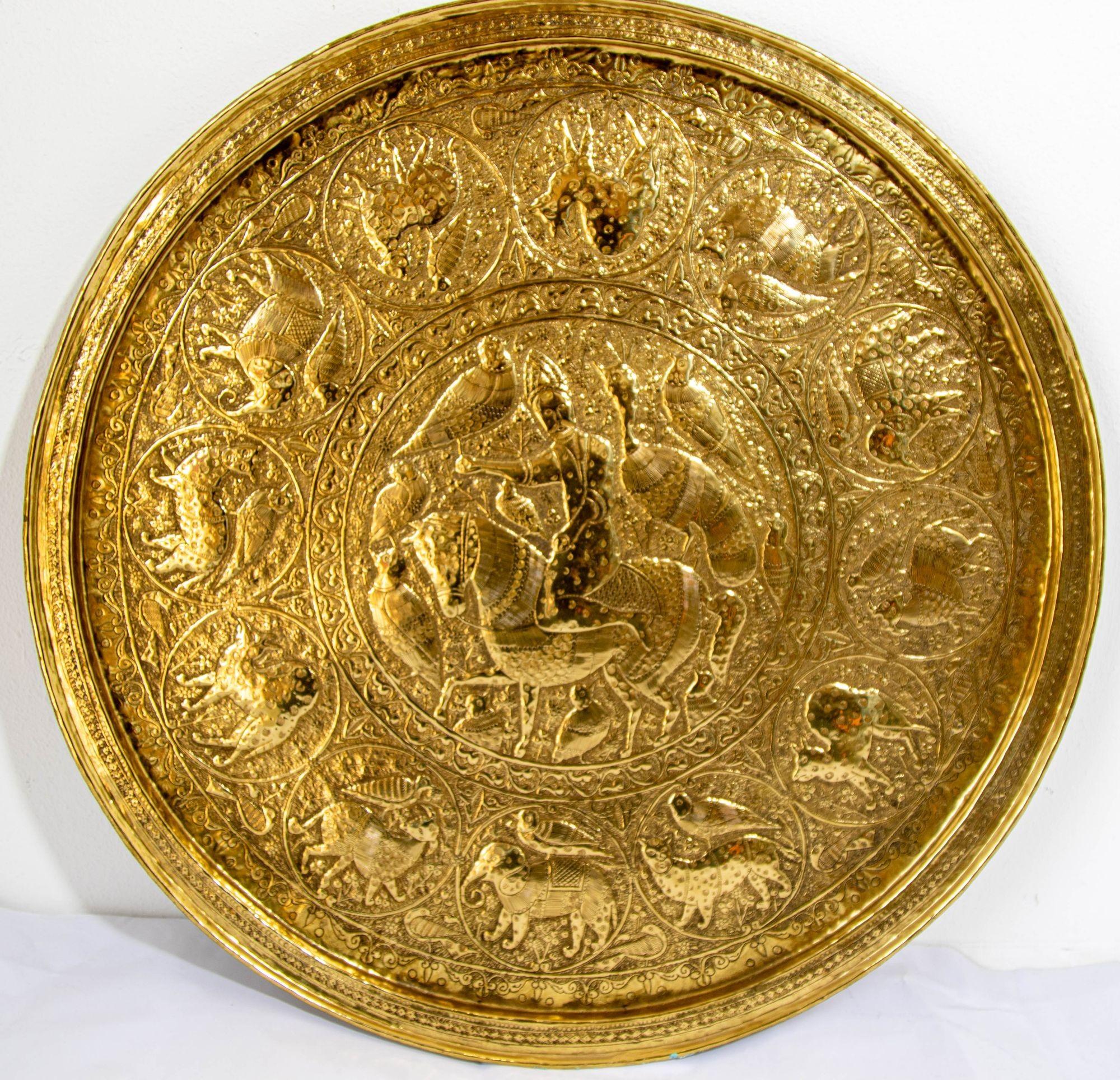 A large and impressive Qajar style circular brass tray, early 20th century.
Measures: 24 1/2 in. diameter.
Heavy metal brass finely hand chased, engraved, and punched.
The handcrafted circular brass platter is decorated and hammered, the center