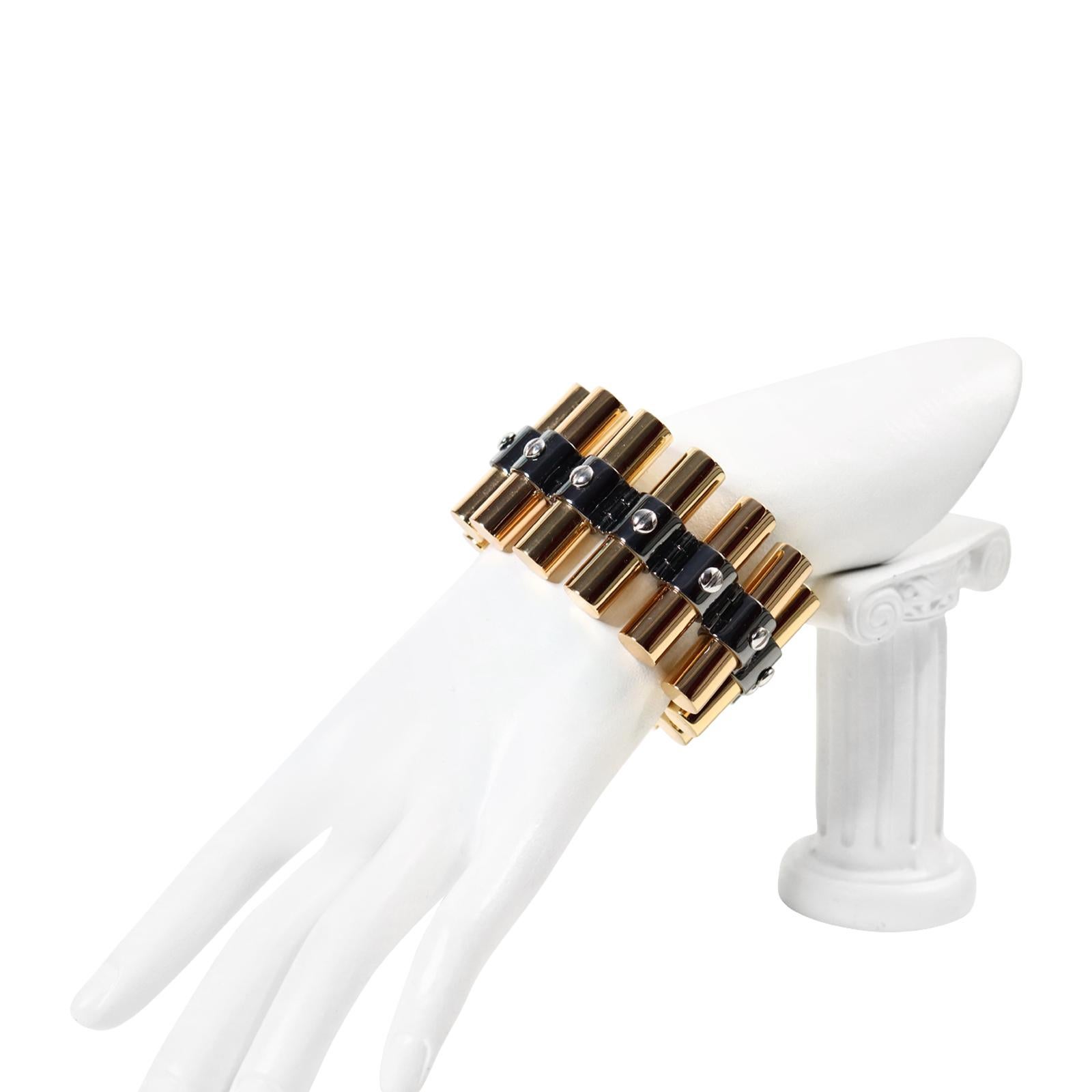Collectible Reed Krakoff Gold Tone Heavy Link Bracelet Circa 2000s. This bracelet is made of tall round cylinders that have dark grey metal with a screw in the middle of each one going all the way around. At the end is a mechanism that lifts up, so
