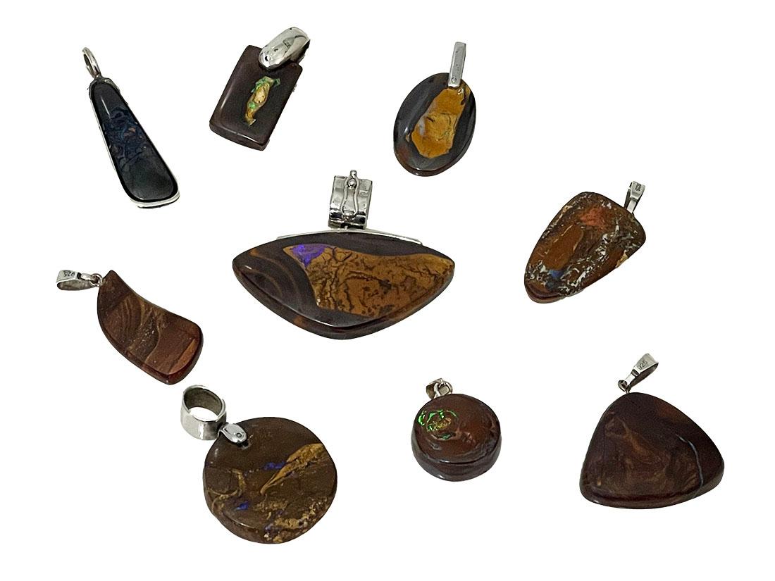 Collection Boulder opal pendants with silver

Nine small boulder Opal pendants with silver eyelets. Two round shapes, two triangular, of which the smaller one has a small chip. An elongated silver setting with a Boulder Opal. A small oval and a