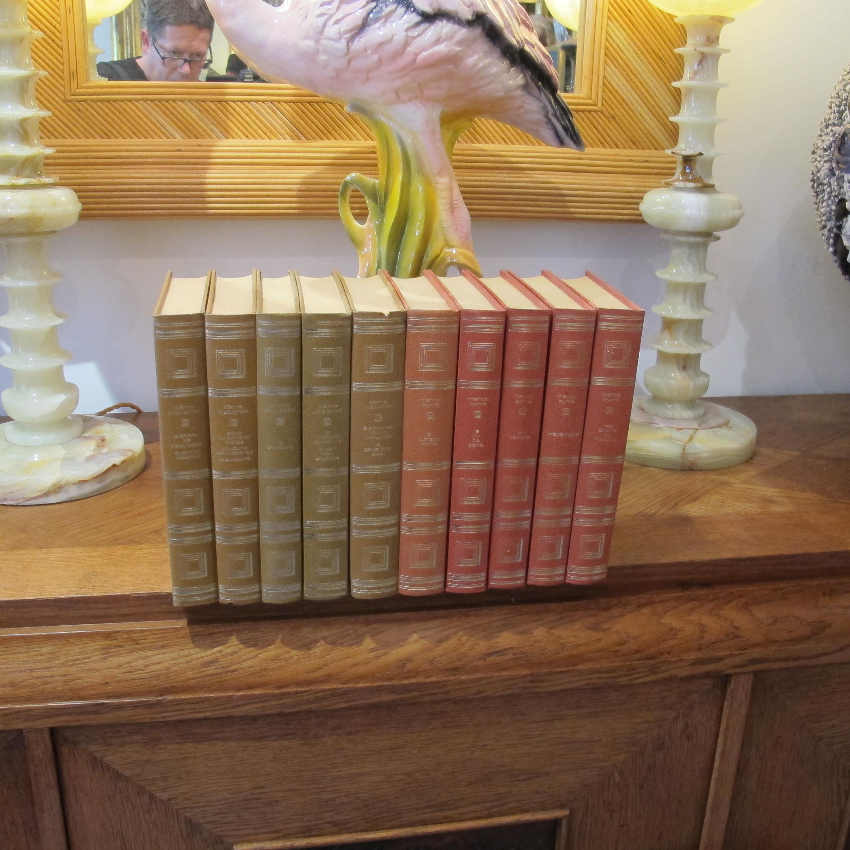 A handsome set of ten vintage early 1970s French literary works, attractively bound in uniform decorative hardback editions with gilt-stamped spines and geometric covers. The collection includes five volumes by Marcel Aymé in red bindings (La Jument