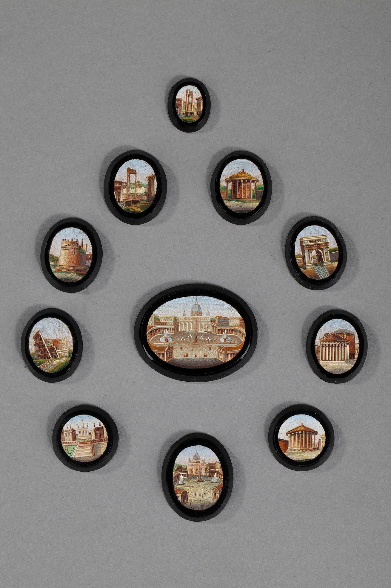 Ensemble de 11 micro-mosaïques Empire sur pierre noire, de forme ronde, ovale ou en goutte d'eau. Ils représentent des édifices romains, tels que le Panthéon, le temple de Vesta ou Saint-Pierre. 

Dim du plus grand : 4,4cm x 3,5cm x 0,4cm
Dim du