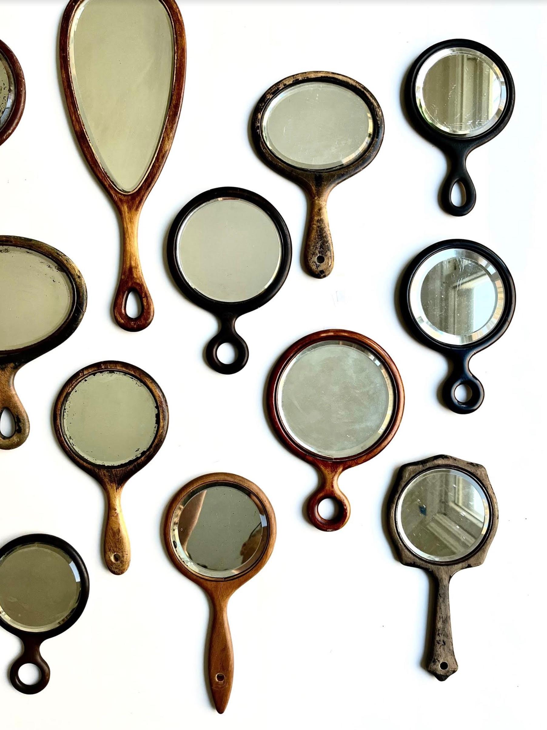 A collection of 16 antique and vintage classic America wooden hand mirrors of various shapes and sizes with beveled glass. The mirrors range in height from 7