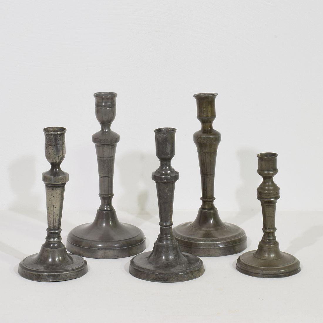 Incredibile collezione di cinque candelieri in peltro. Sono tutti diversi e unici,
Francia, circa 1750-1850.
Intemperie, ammaccature e piccole perdite, ma queste imperfezioni contribuiscono ad autenticare questi oggetti in quanto si trattava di
