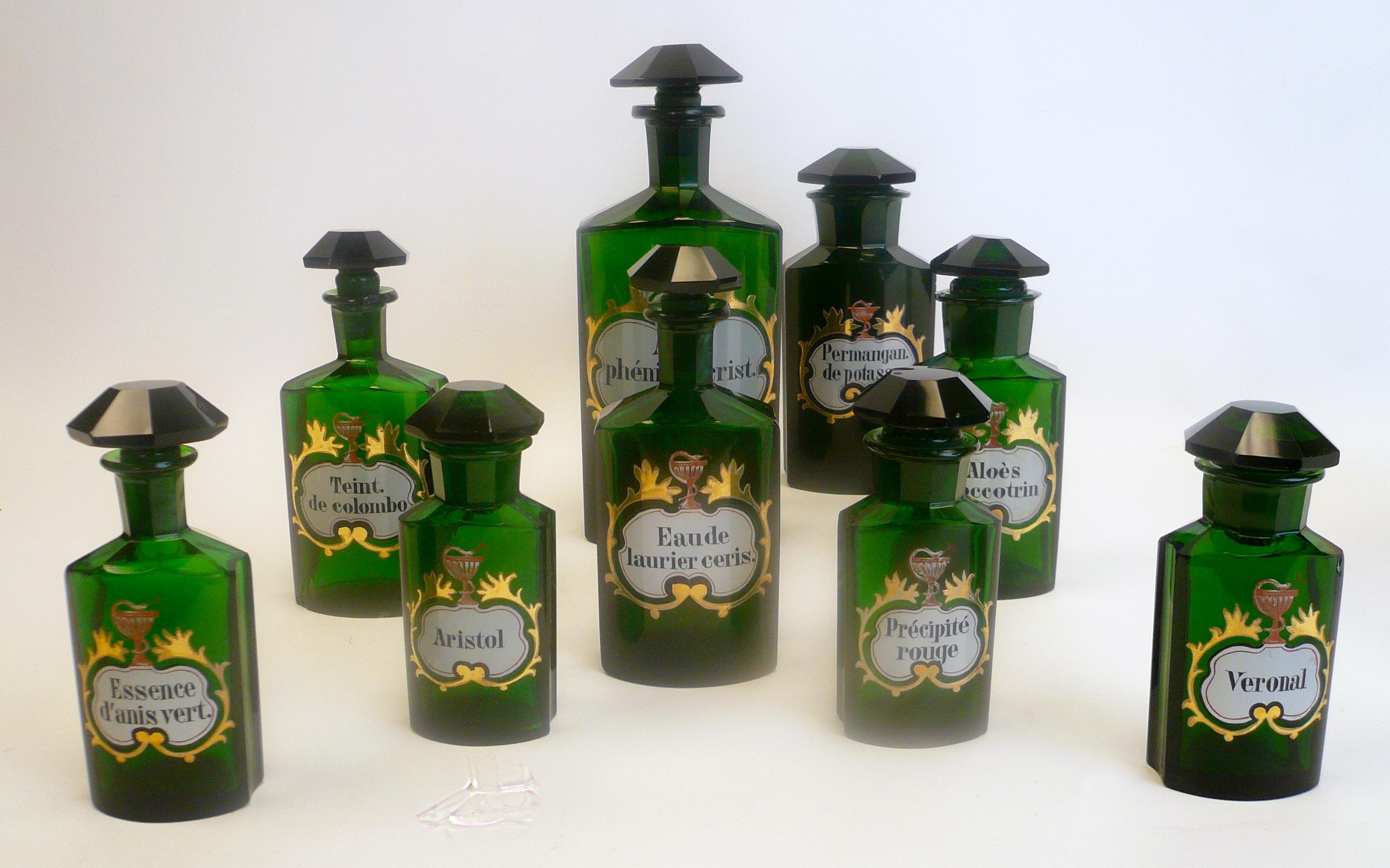 This collection of green panel cut glass apothecary bottles feature hand enameled Latin titles with gilt highlights.