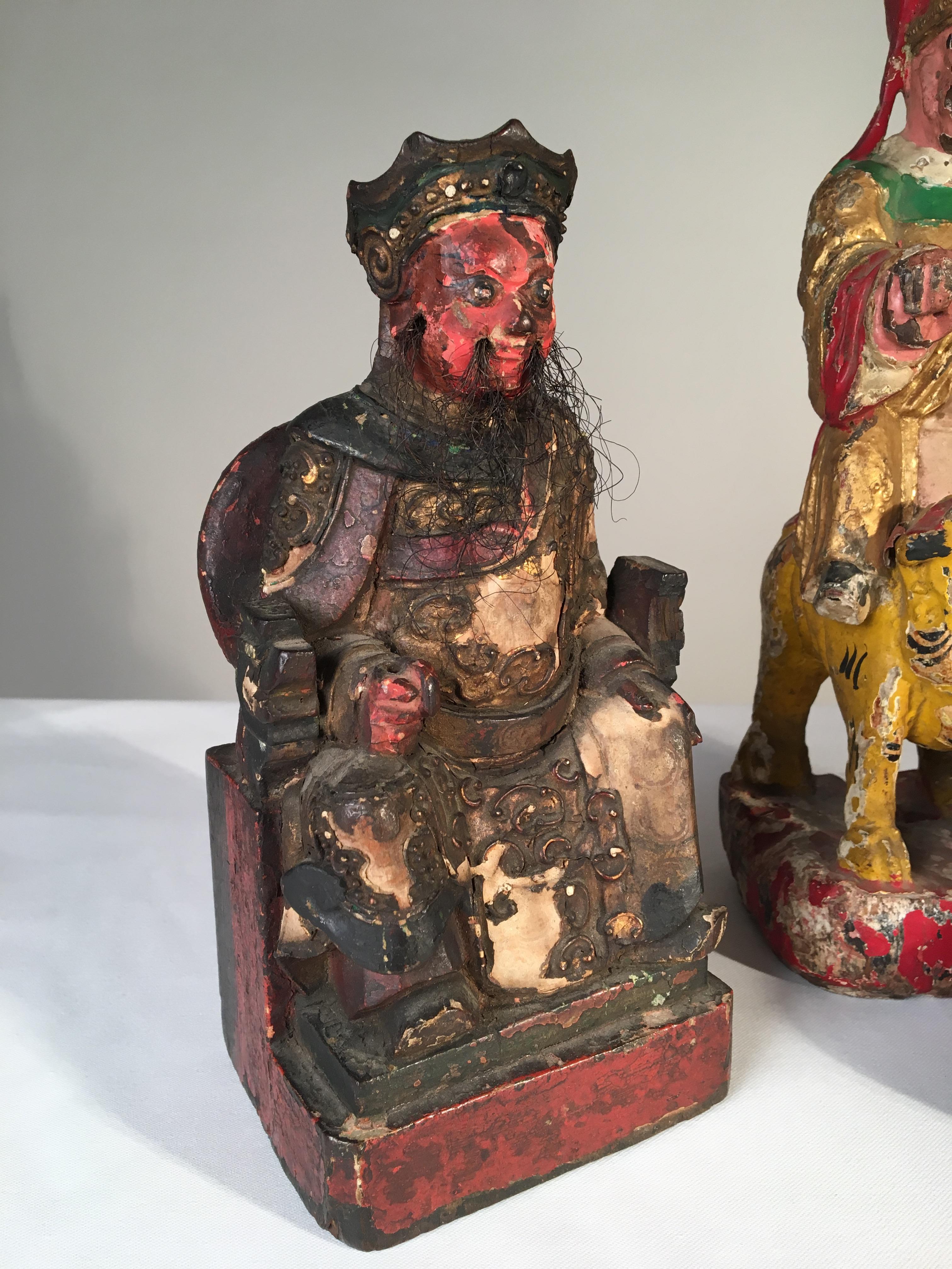 A collection of Folk Art carved figurines depicting Asian religious figures including Chang Tao-ling riding a tiger, seated Confucius, and a seated Buddha.