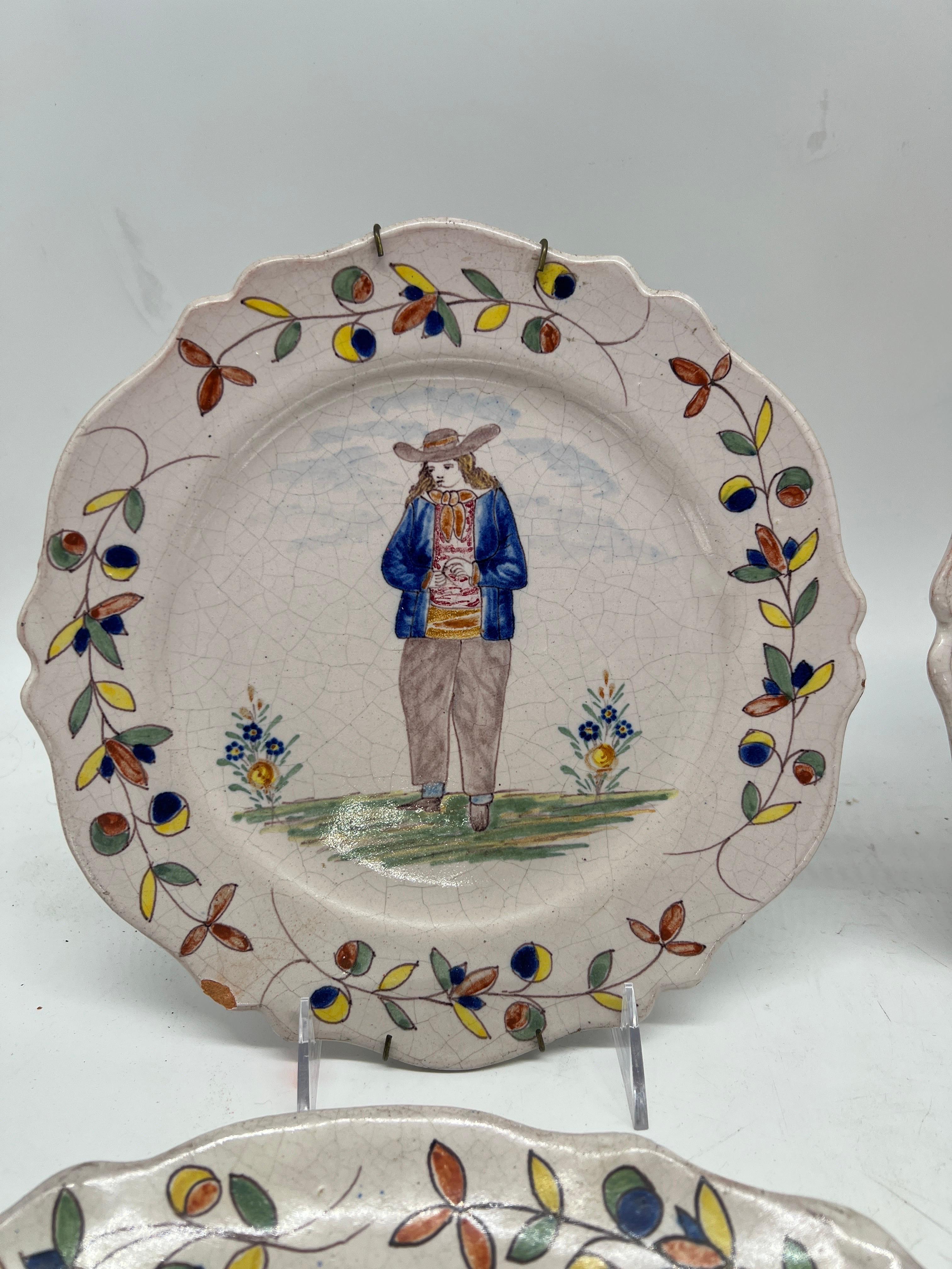 Quimper Pottery, French 20th century.

A collection of 4 vintage Quimper faience pottery plates. Each plate has a hand painted and tin glazed figural surface and accented by a polychrome foliate leaf border. Marked to verso.

Platter: 12.25