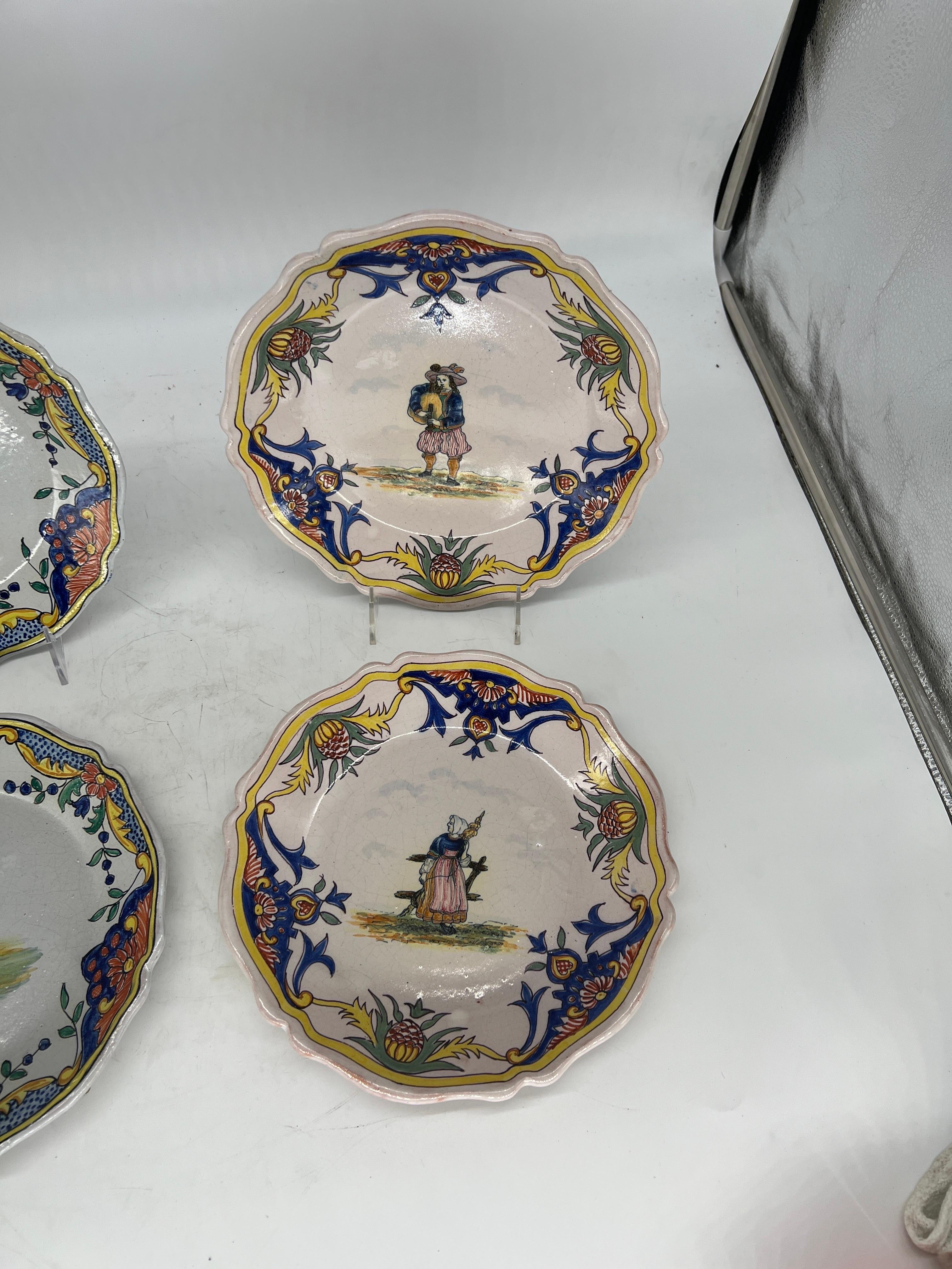 Quimper Pottery, French 20th century.

A collection of 4 vintage Quimper faience pottery plates. Each plate has a hand painted and tin glazed figural surface and accented by a polychrome foliate leaf border. Marked to verso.