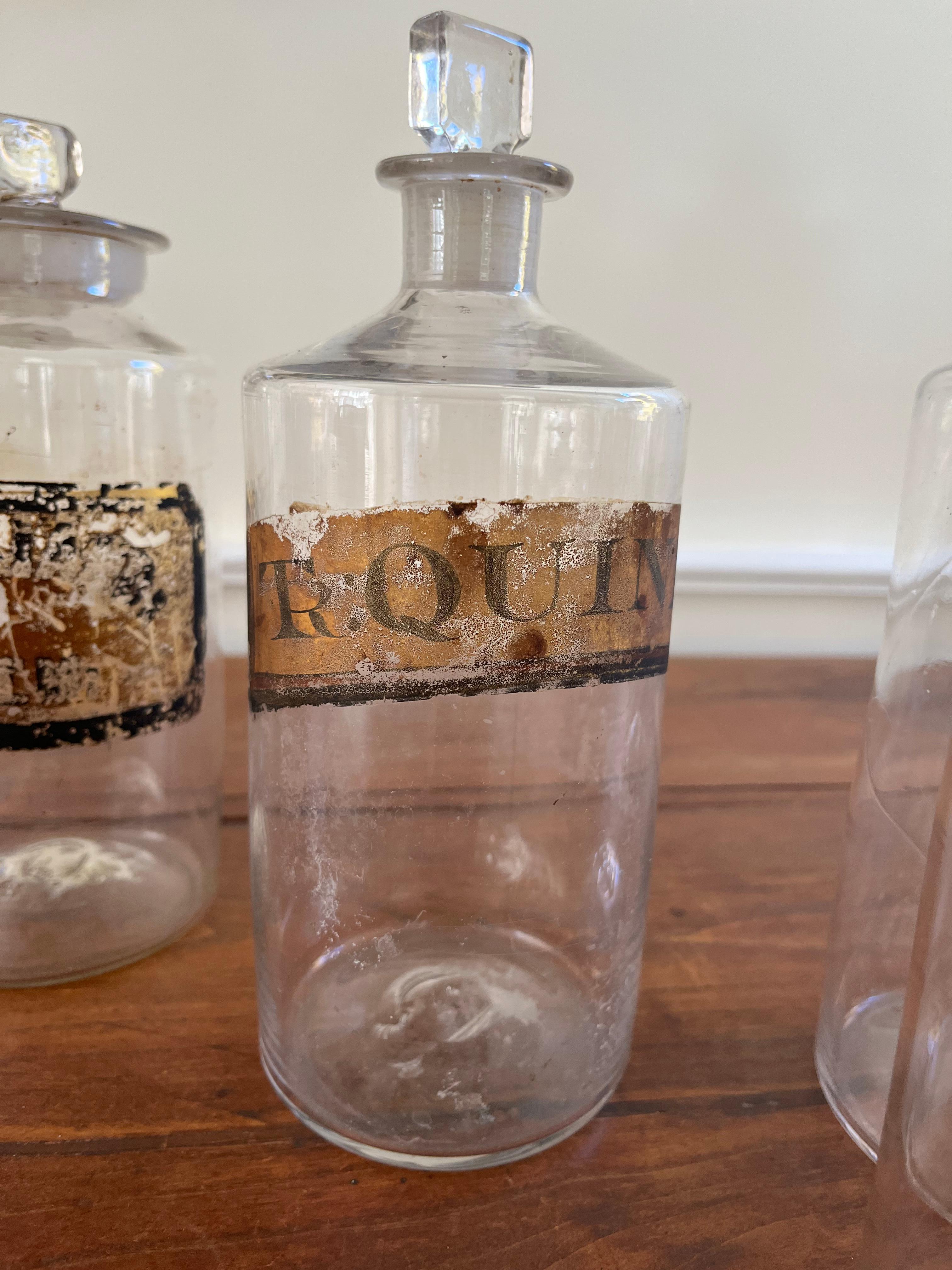 Une belle collection de bouteilles d'apothicaire, certaines avec des étiquettes et des traces de décoration dorée, vers 1850, soufflées à la main avec des marques de pontil polies sur la base, et conservant leurs bouchons en verre d'origine.