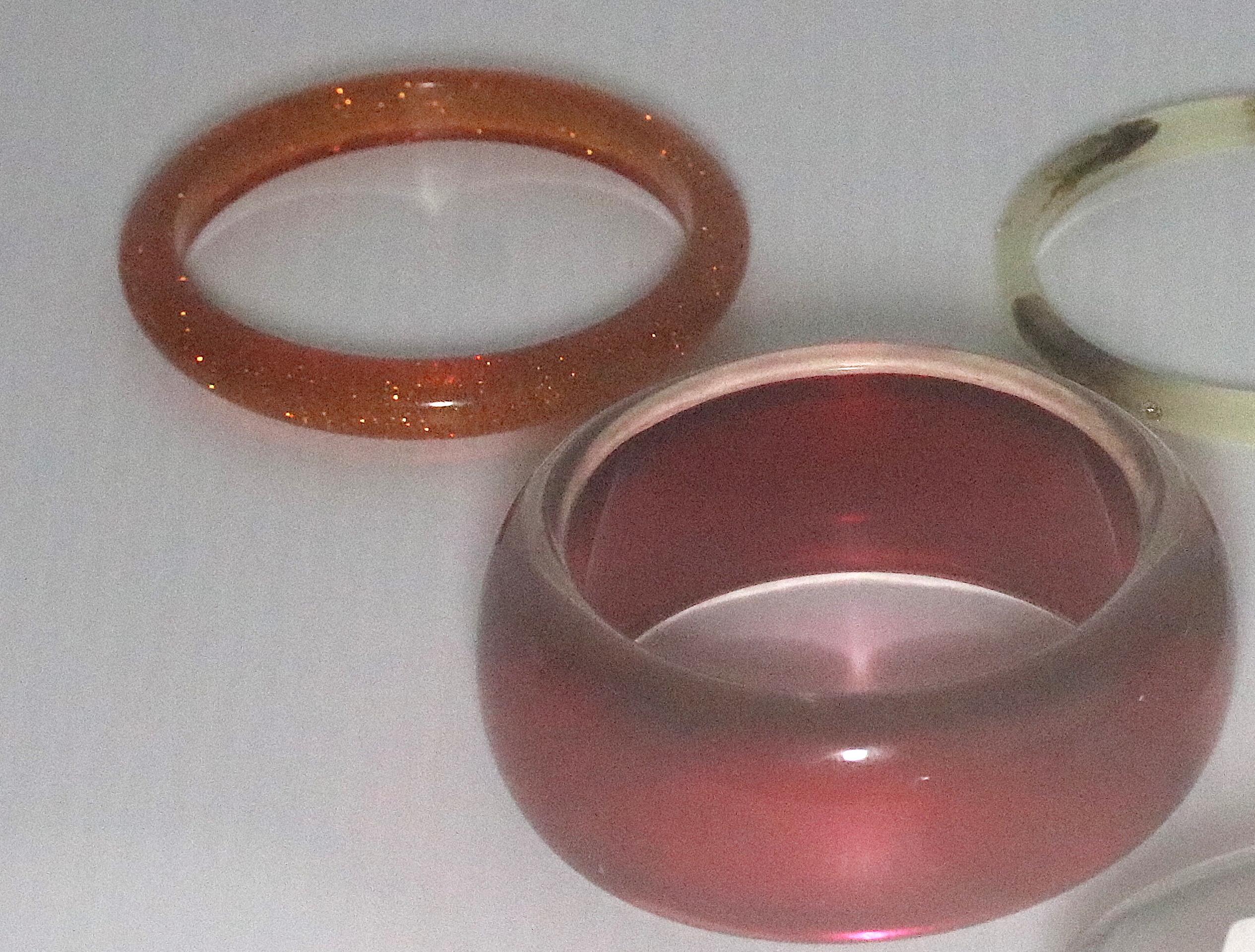 A Collection of 5 Bangle Thermoplastic Bracelets-2 translucent red, 1 translucent gold and 1 translucent silver, both with inset sparkles,  from the 1950s and one Tortoise lucite with 5 cz's inset all around from Alexis Bittar- 1990s  

all standard