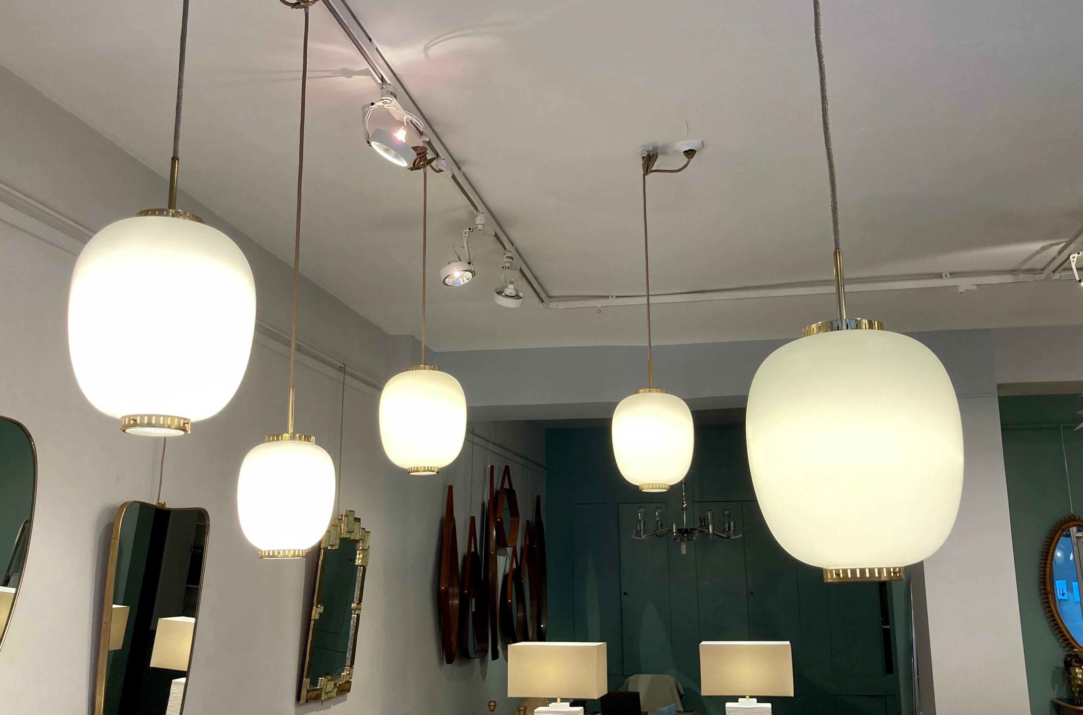 Collection of 5 opaline glass and brass ceiling fixtures.
See dimensions below 
Designed by Bent Karlby for Lyfa. 
Denmark, late 1950s.

Dimensions: (Height of the opaline + top and bottom brass disc)
Medium (4 items available) H 11.8 in. (30 cm), D