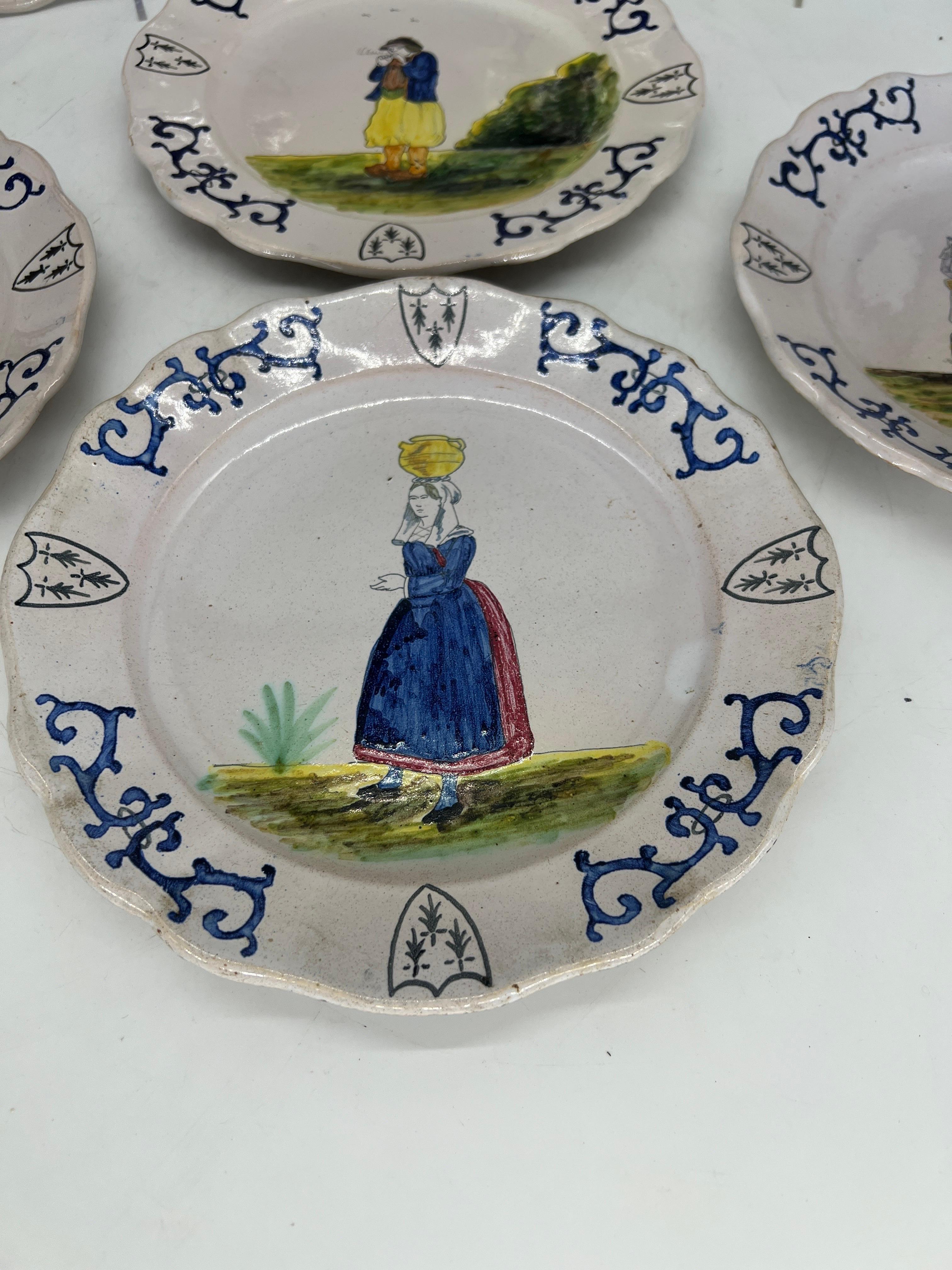Quimper Pottery, French 20th century.

A collection of six vintage Quimper faience pottery plates. Each plate has a hand painted and tin glazed figural surface and accented by a polychrome vine border, armorial shields and a scalloped edge. Marked