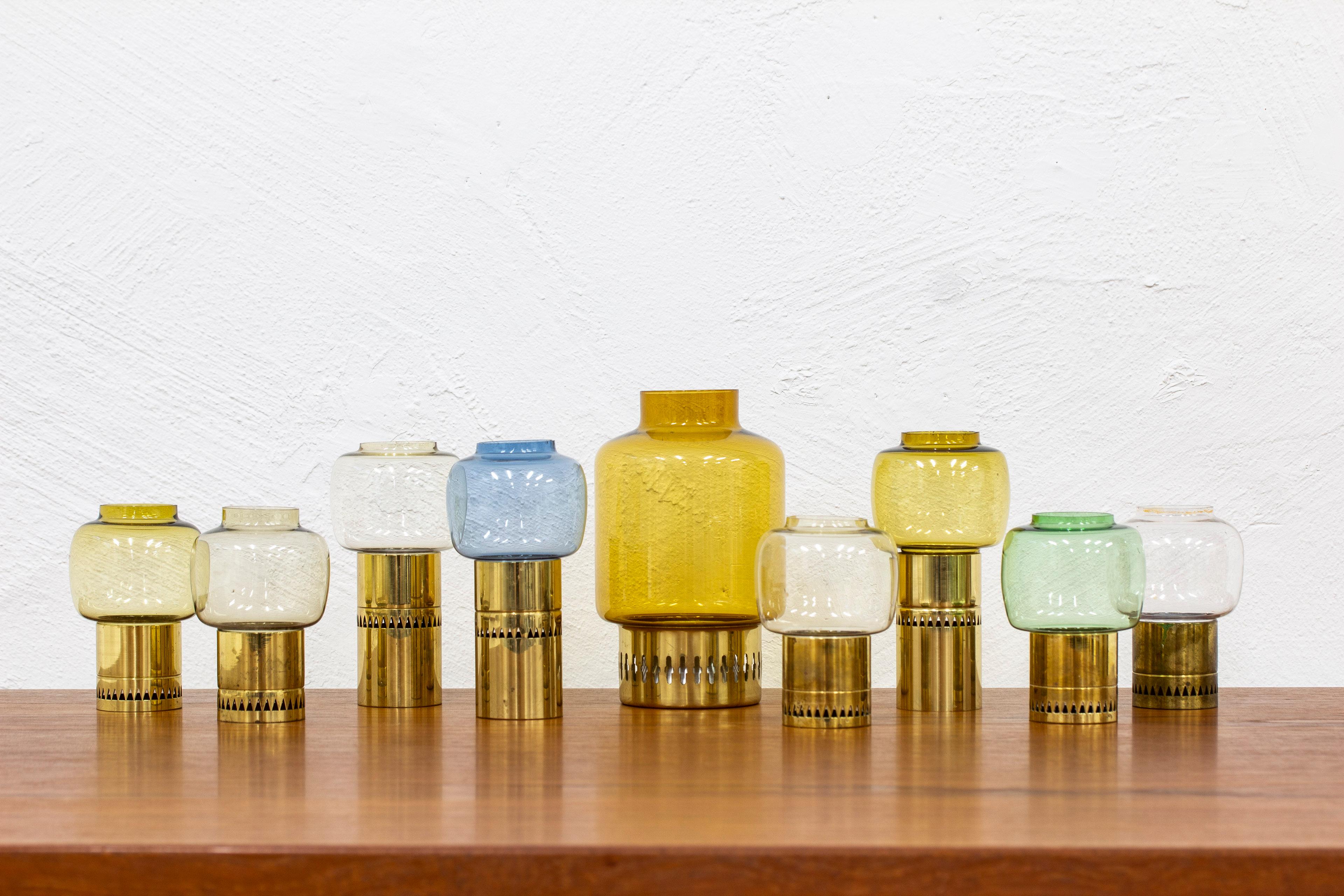Candle holders designed by Hans-Agne Jakobsson. Produced by his own company during the 1960s. Made from solid brass with multicolored glass shades. Good vintage condition with some age related wear and patina. Blue glass with tiny chips to the top