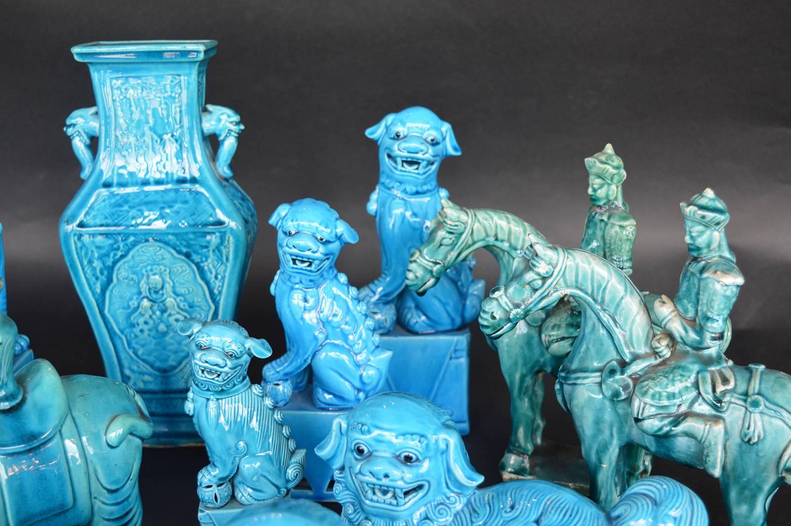 Collection of turquoise foo dogs, elephants, horses and immortals with a pair of bookends set in brass and a vase. The age of the pieces vary, the more yellowed pieces are older and the more vibrant blue pieces are newer.