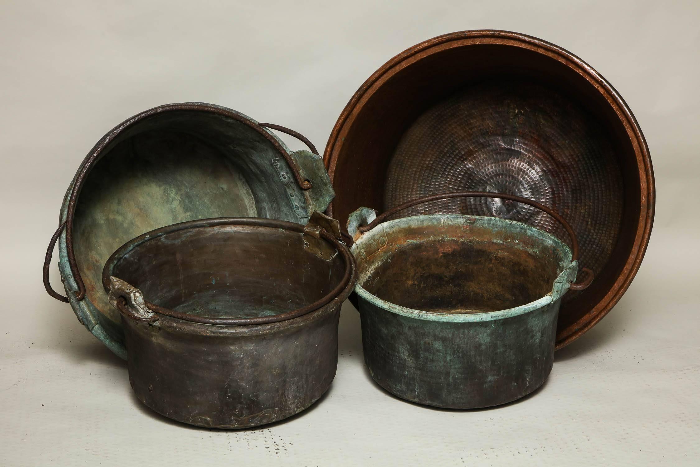 A collection of four copper containers useful next to a fireplace for logs.

A weathered copper container
A copper container with a weathered surface, flared sides and rolled rim and a wrought iron carrying handle mounted on riveted hinge ears.