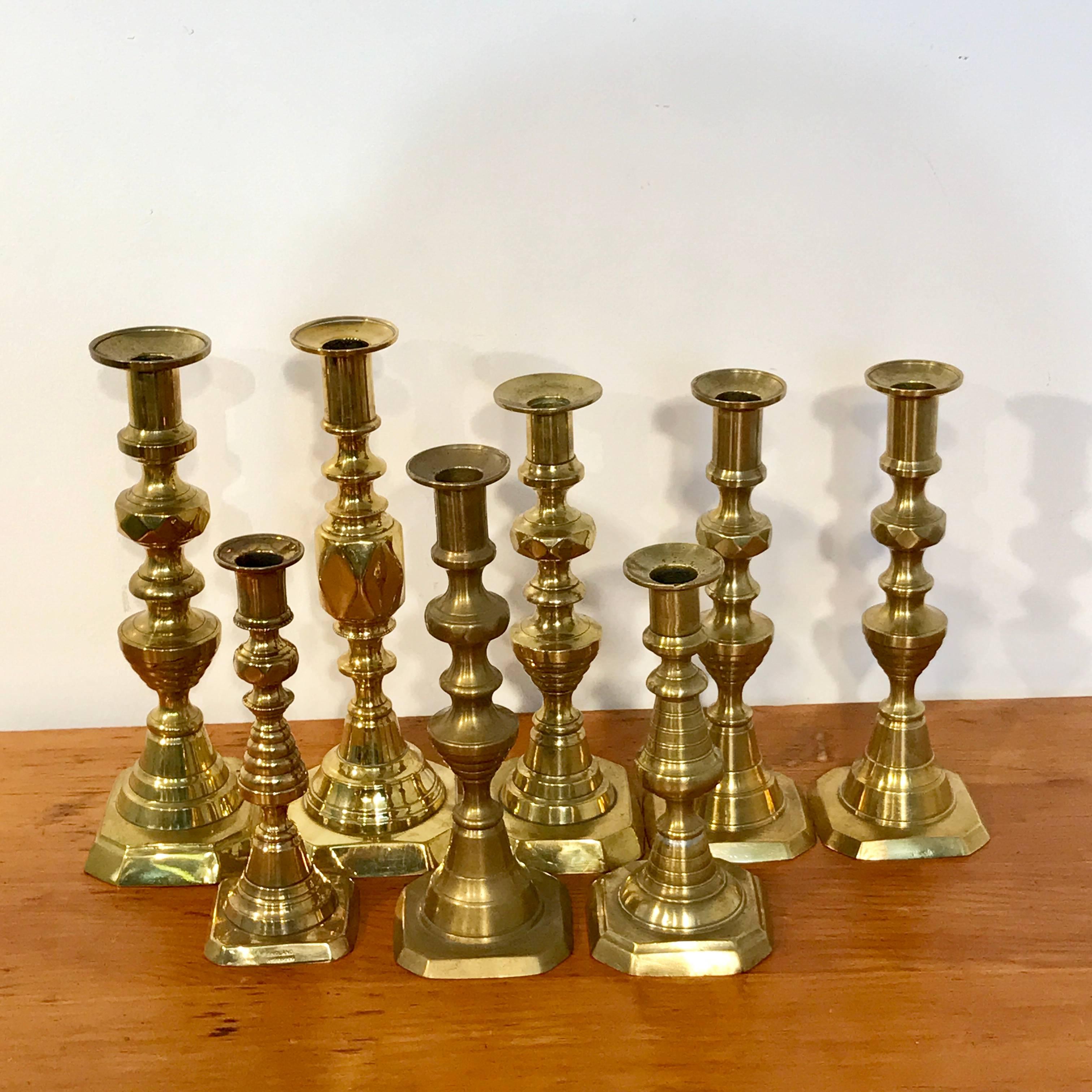 A collection of eight antique English brass candlesticks, varying heights from 11