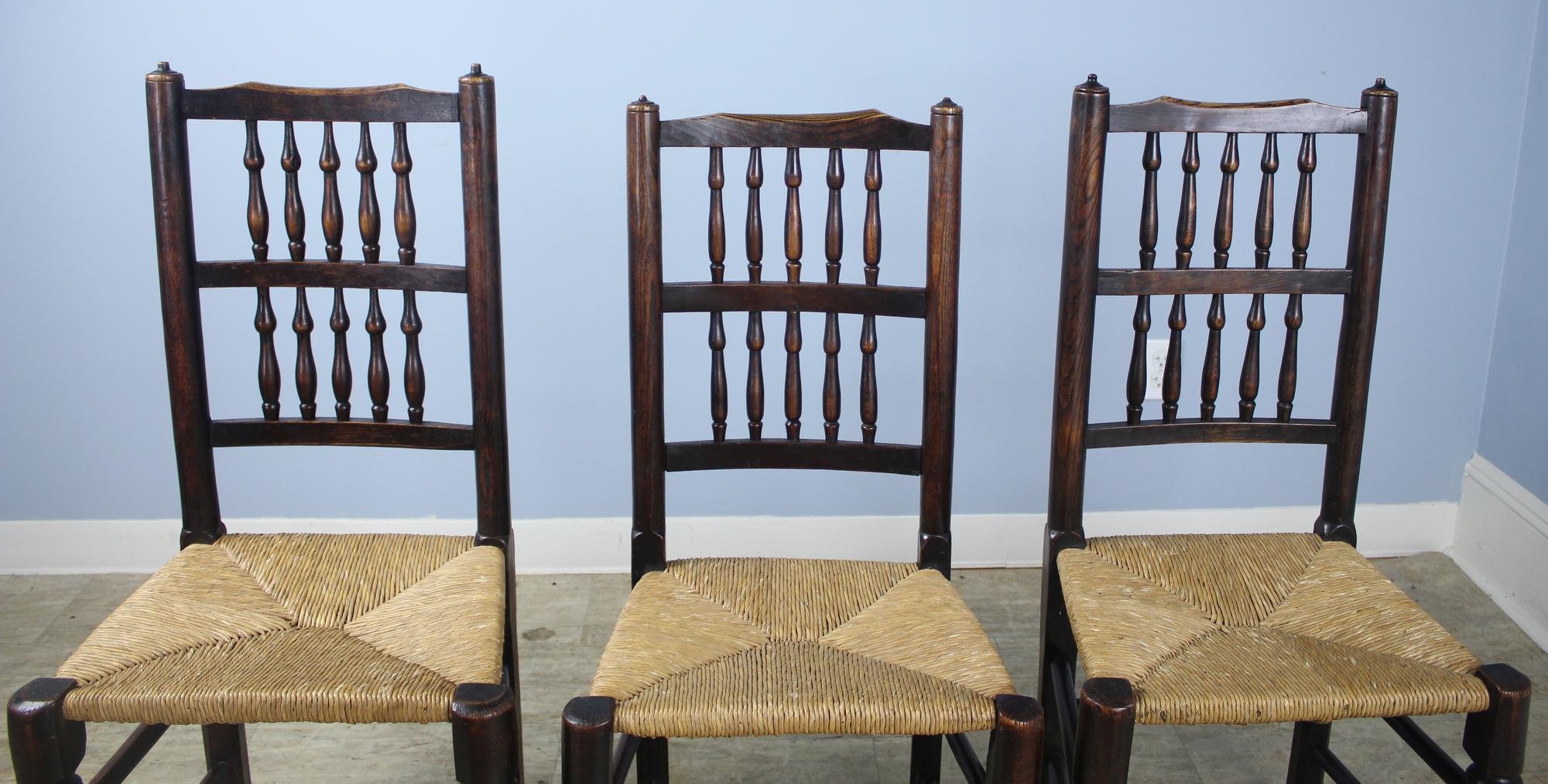 A collection of 8 country spindleback chairs, with nice color and patina. They are very much handmade and are possibly a marriage of two different sets from the same maker. The back heights, seat heights, widths and depths are similar but not