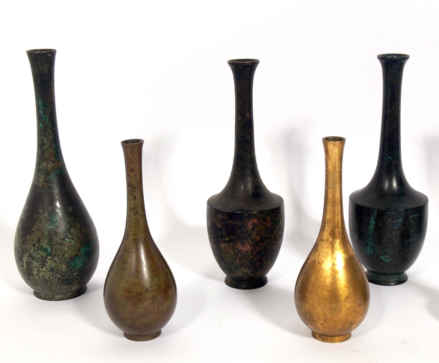 Collection of eleven Japanese bronze vases, Japan, 20th century. They all exhibit sculptural forms and have a wide range of patinas from deep browns and golds to warty verdigris greens. The largest measures 9