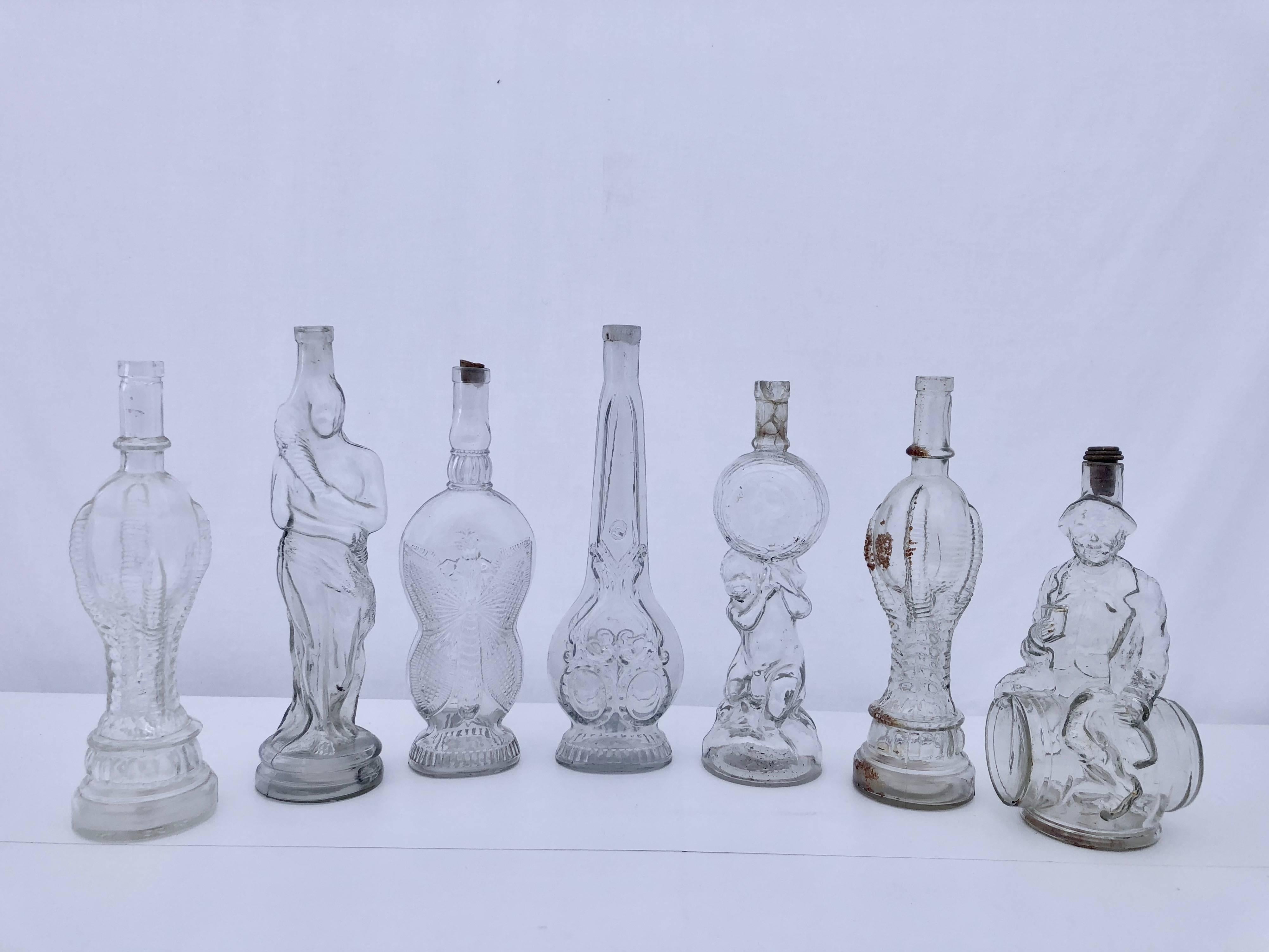 This is a fun collection of 13 antique French collectible glass bottles in a variety of figures. All are transparent glass except one which is a pale pink colored glass.
The collection consists of:
Six bottles are in the shape of people
Two