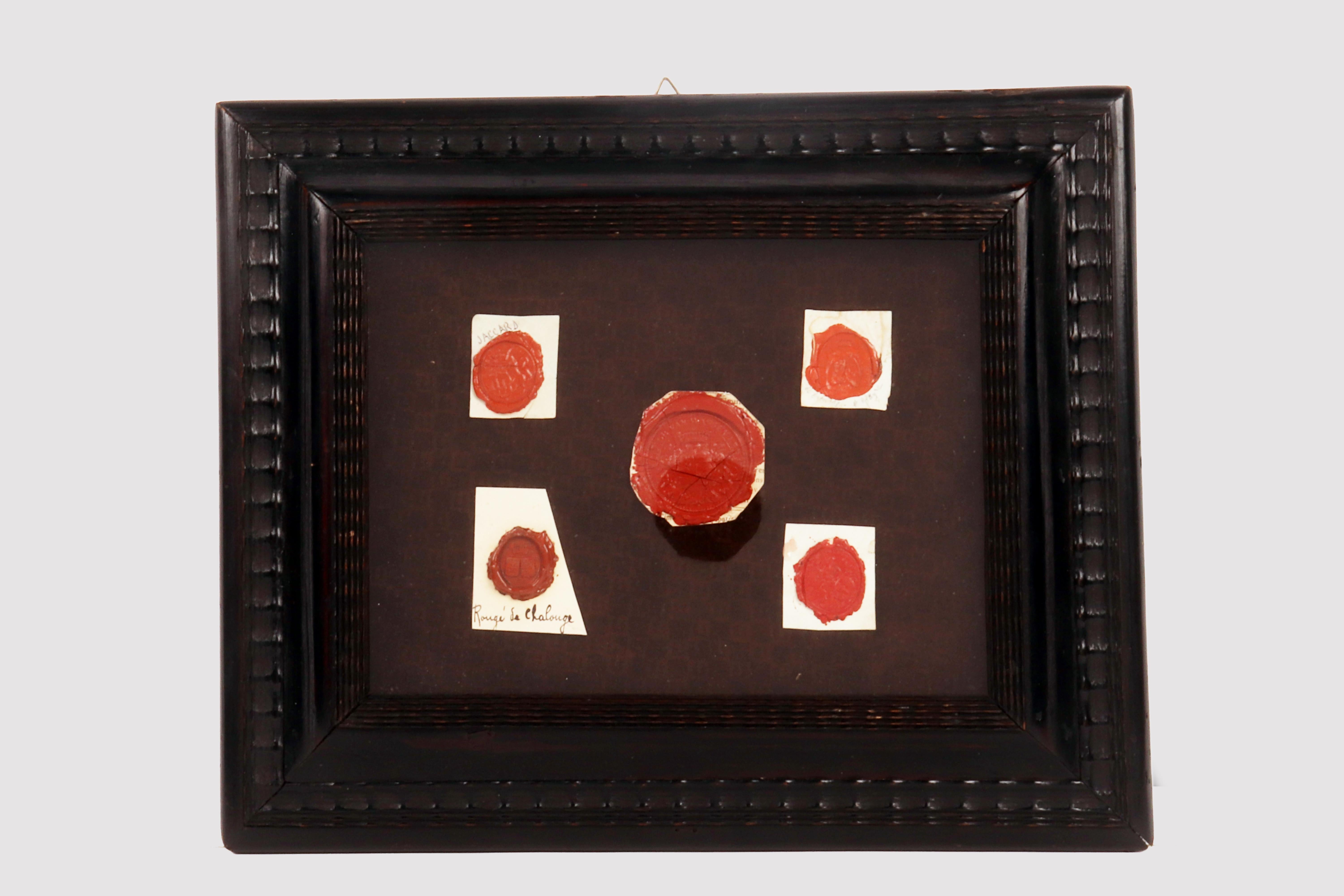 The collection is contained in a guilloche frame with a wavy edge. Inside there is a panel covered in velvet on which five sealing wax stamps are applied. The seals, clockwise from top left, belong to an unidentified Jaccard family, to Marie