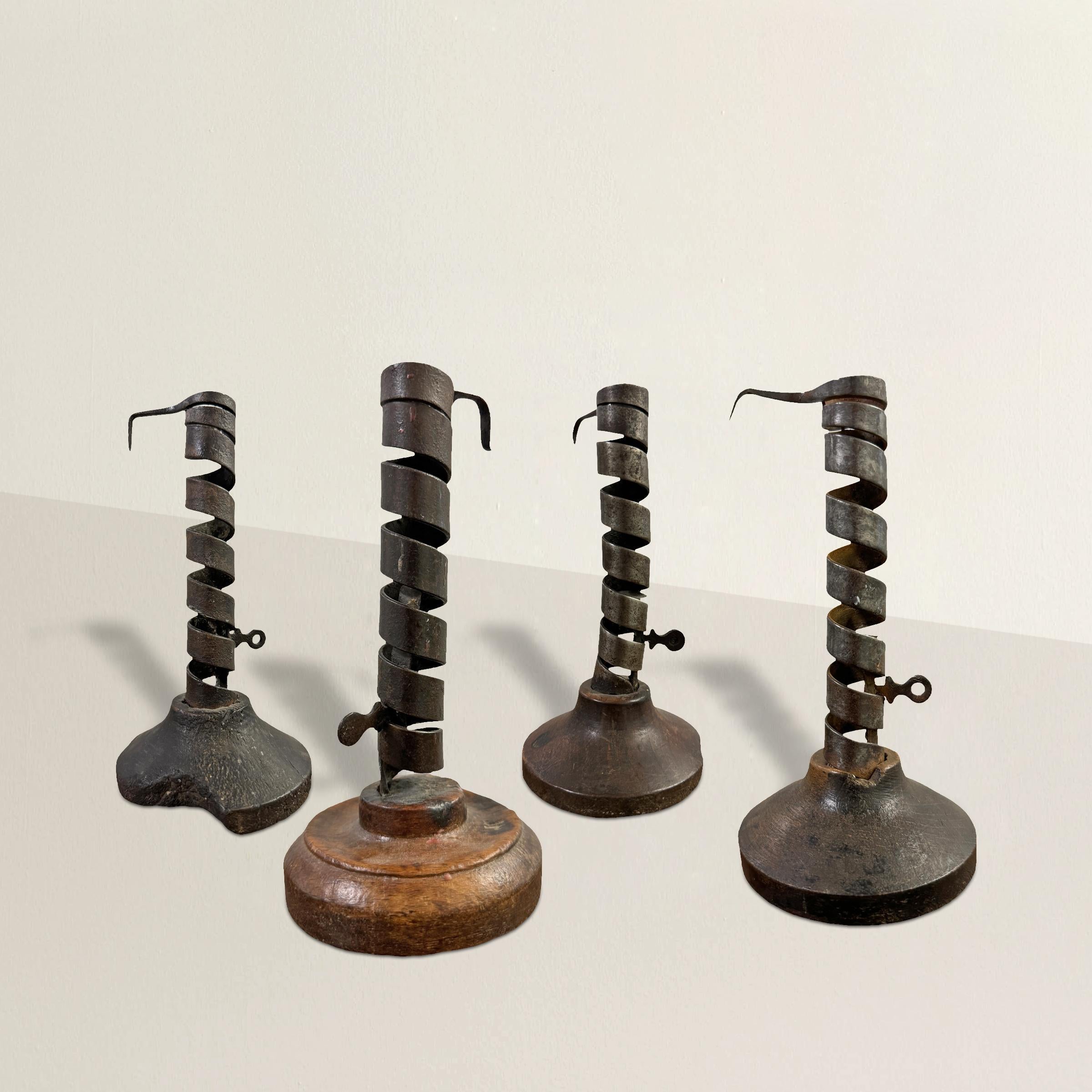 Step back in time with this collection of four 18th-century French candlesticks, each a testament to the simplicity and functionality of primitive craftsmanship. Made from hand-wrought iron, these candlesticks feature spiral stems forged by skilled