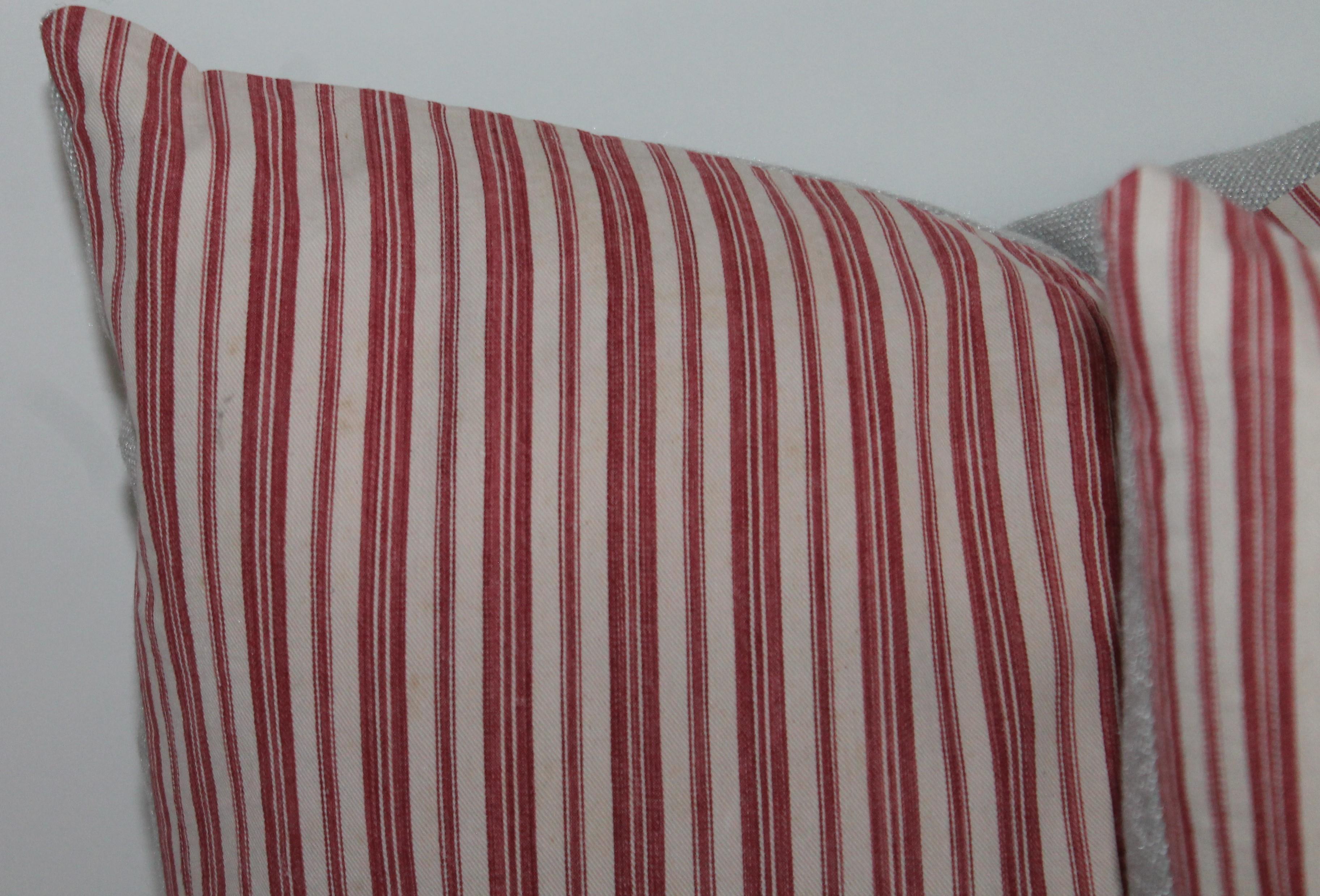 This collection of four 19th century red and white ticking pillows are in fine condition. The inserts are down and feather fill. The backings are in cream cotton linen.