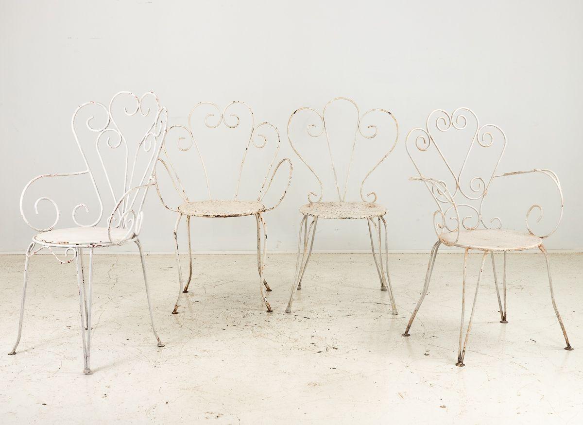 A delightful set of four similarly styled white painted metal French bistro chairs, designed to infuse your space with an air of elegance and charm. These chairs feature lovely scrollwork on both the arms and legs, a design element reminiscent of