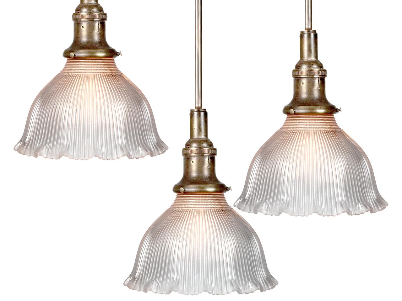 We have a collection of these small Holophane pendents. They are priced and sold per lamp. They are prismatic glass but have a soft delicate look.
The shade is frosted with a pleasing ruffled bottom edge. The socket is early and original. Its signed