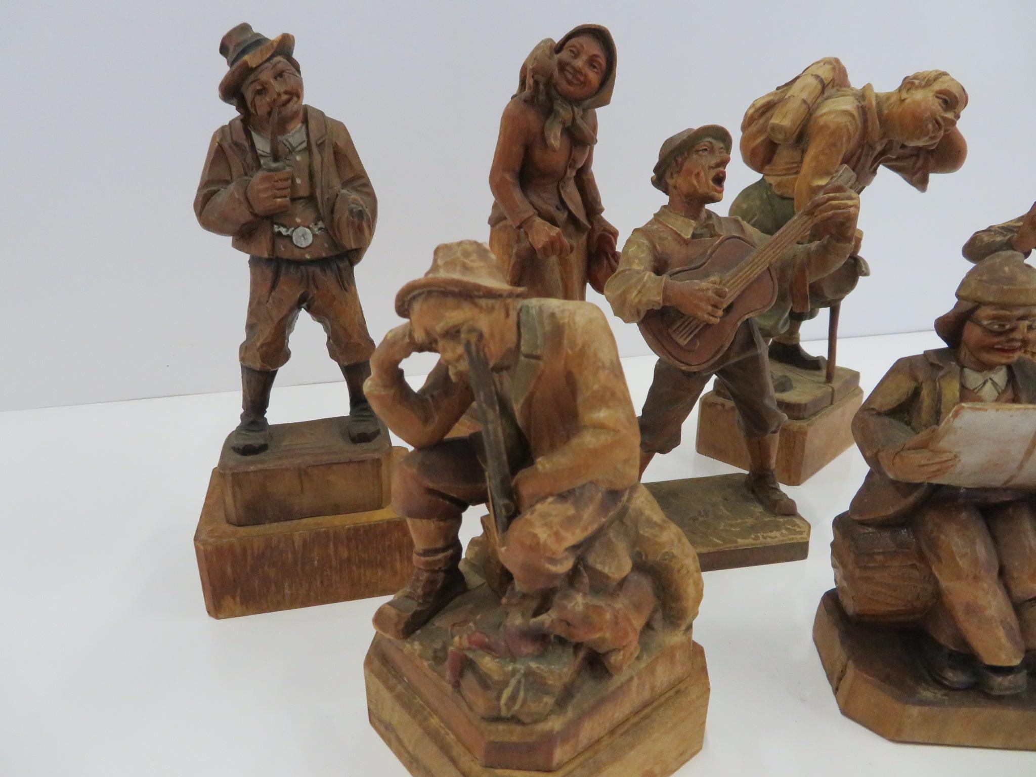 Wonderful collection of seven Anri and Black Forest deftly hand-carved and hand-painted Folk Art figures all in olden times native dress featuring an old lady with a cat on her shoulder, a hiker wiping sweat from his neck, a seated couple reading a