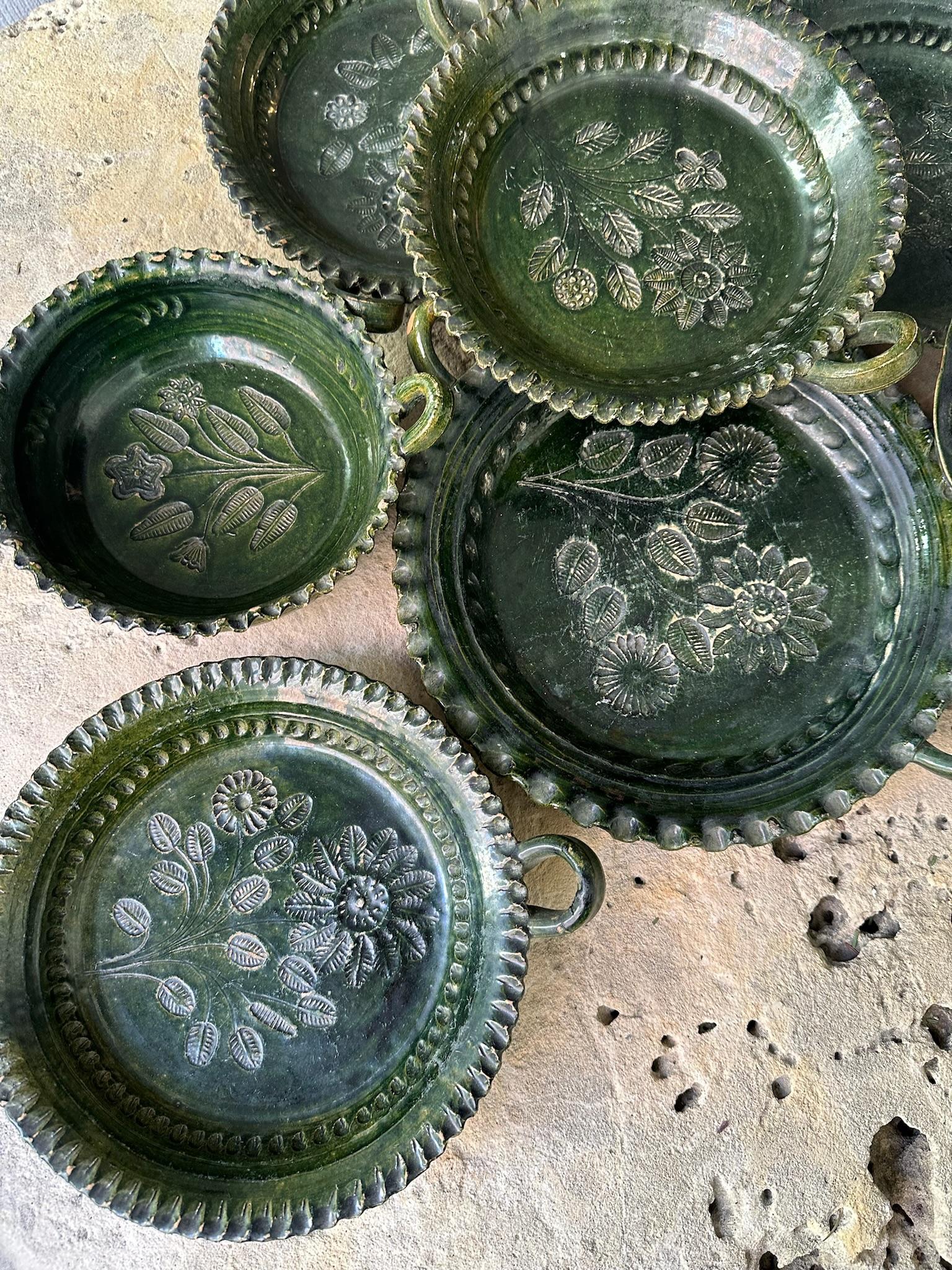 Collection of 8 Vintage Mexican Green Glaze Ceramics circa 1940s. Round ceramics with floral and leaf designs etched into the clay and etched rims with handles on each piece.
Dimensions of the 8 Pieces:
7 in L x 4 in W
3 in L x 9 in W
13 in L x 10.5