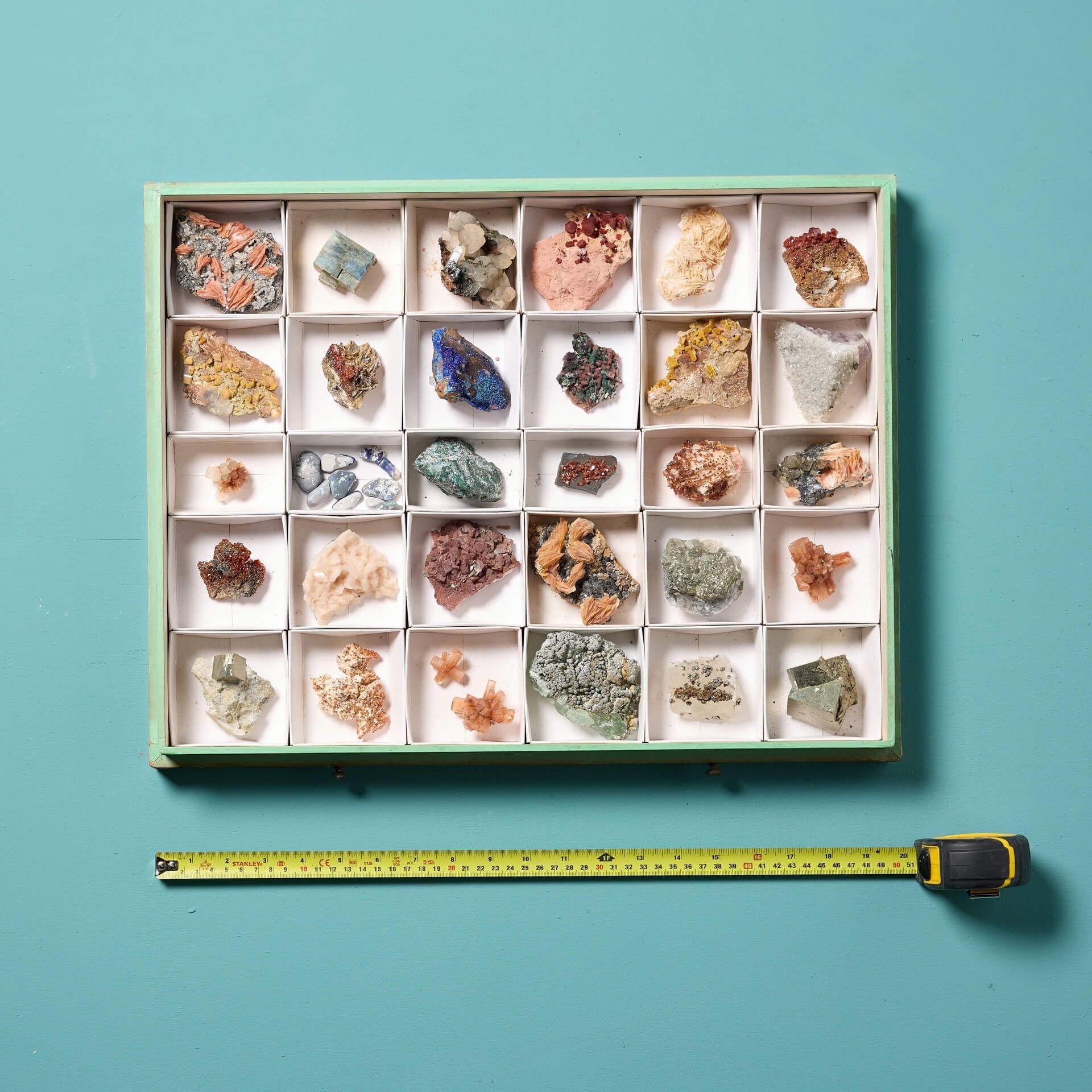Eine Sammlung von Museumsmineralien in einer Vitrine mit abnehmbarem Deckel. Das Set wird in einem eleganten, glasierten Etui mit abnehmbarem Deckel präsentiert und enthält 30 europäische Mineralien, darunter Vanadinit, Stilbit, Azurit und Pyrit,