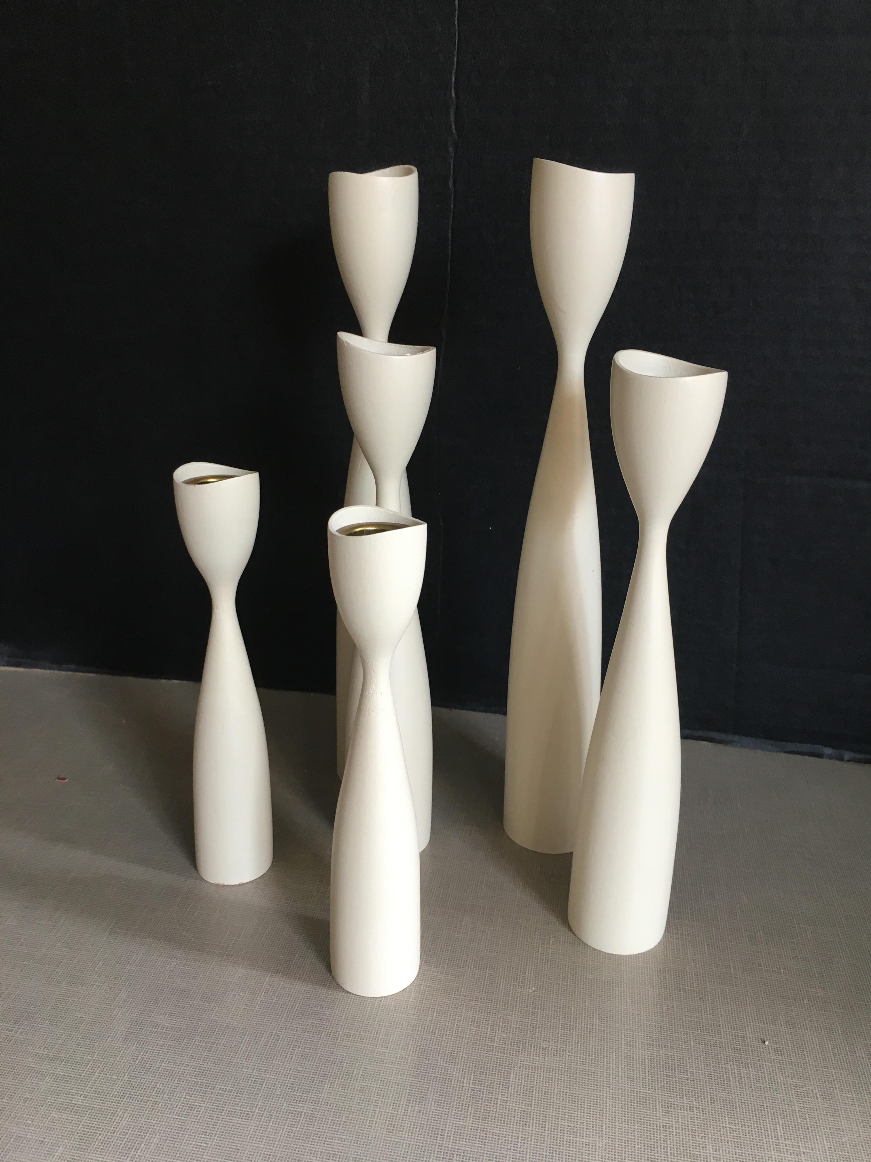 A collection of 6 off-white teak Danish midcentury candlesticks.