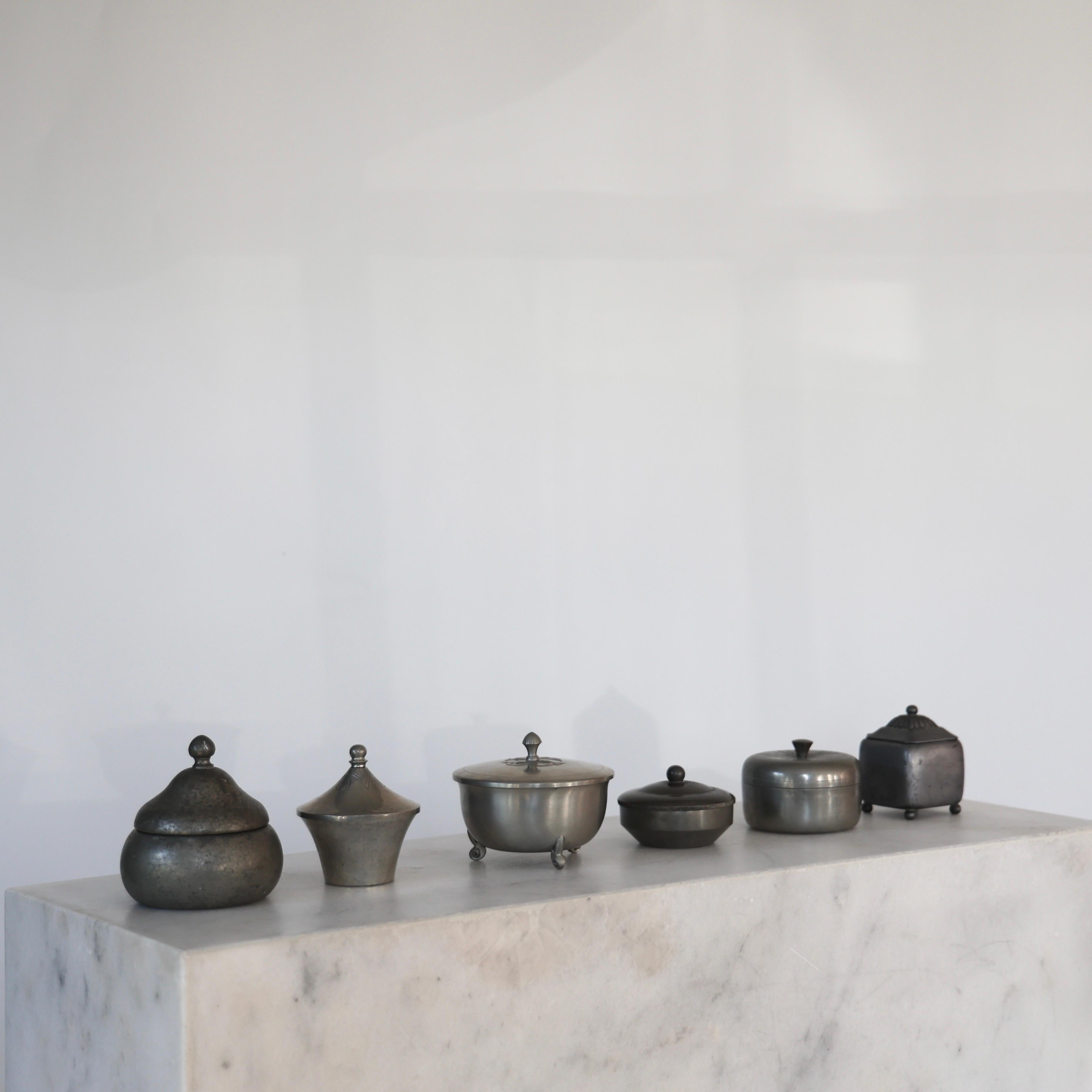 Collection of Lidded Pewter Containers designed by Just Andersen in the 1920s. A exquisite collection for a beautiful place. 

* Six (6) different pewter boxes with lids
* Designer: Just Andersen
* Manufacturer: Just Andersen A/S (5) and GAB Sweden