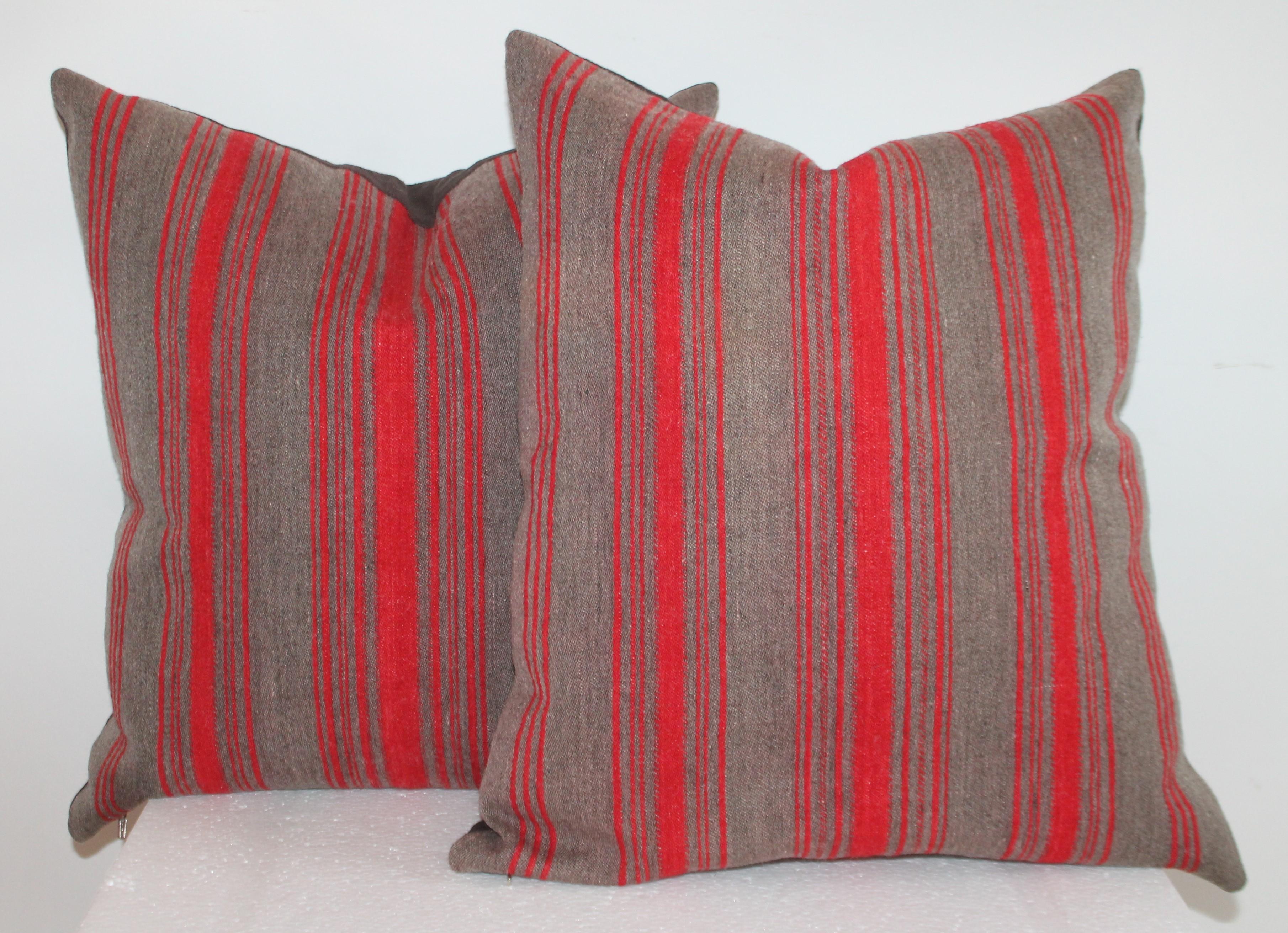 19th century red and grey ticking wool pillows with brown cotton linen backing. The inserts are made of down and feather fill.