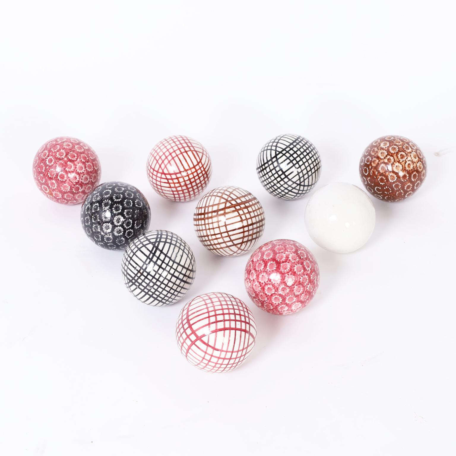 Ten carpet balls crafted in stoneware, decorated and glazed in several different colors and designs including a white cue ball.