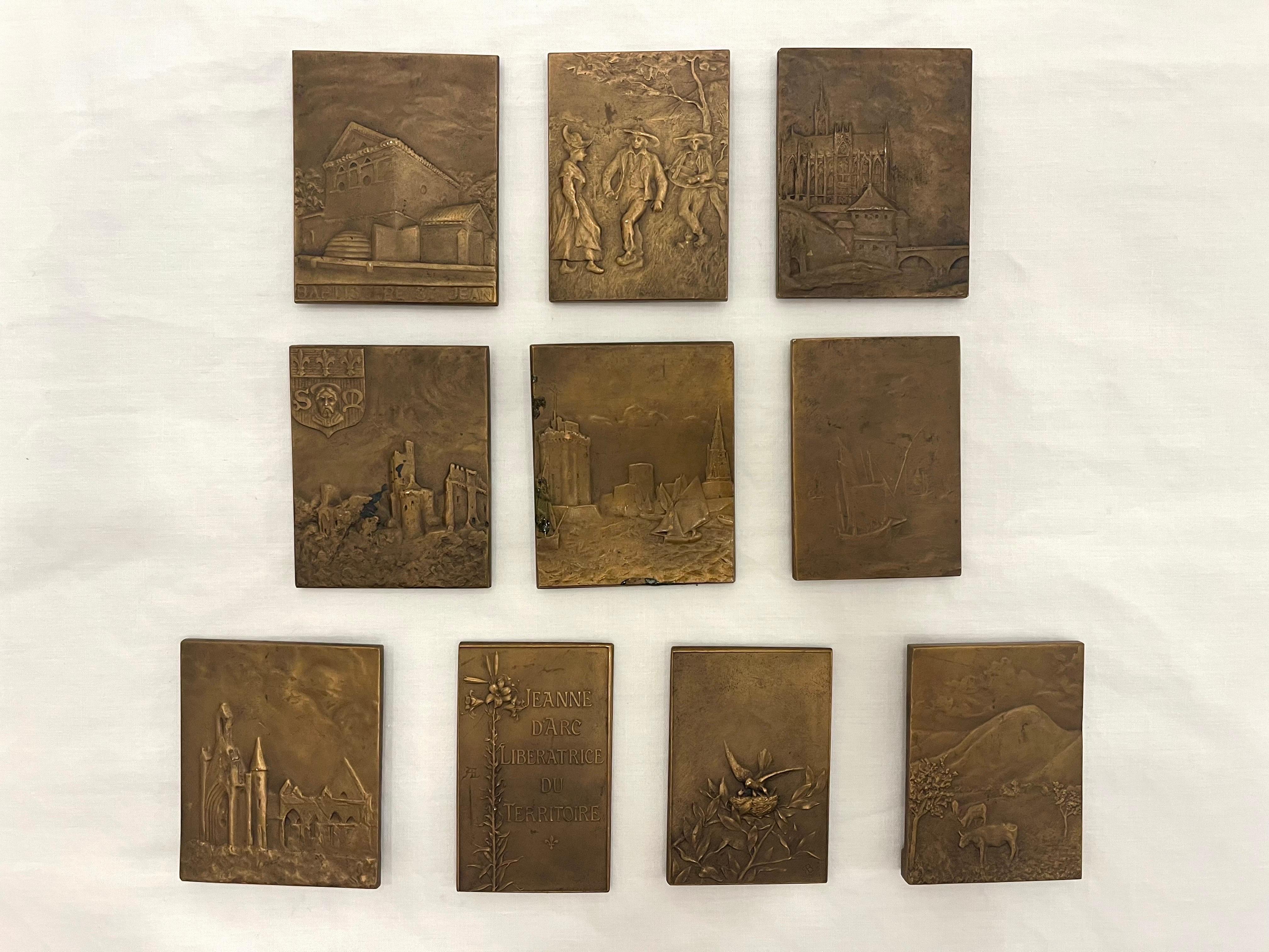 A collection of ten early 20th century medal size bronze bas relief sculptural plaques from France. Eight feature the beautiful headdresses of France. All eight are sculpted and created by the French artist Ernesta Robert-Merignac (1859-1933) whose