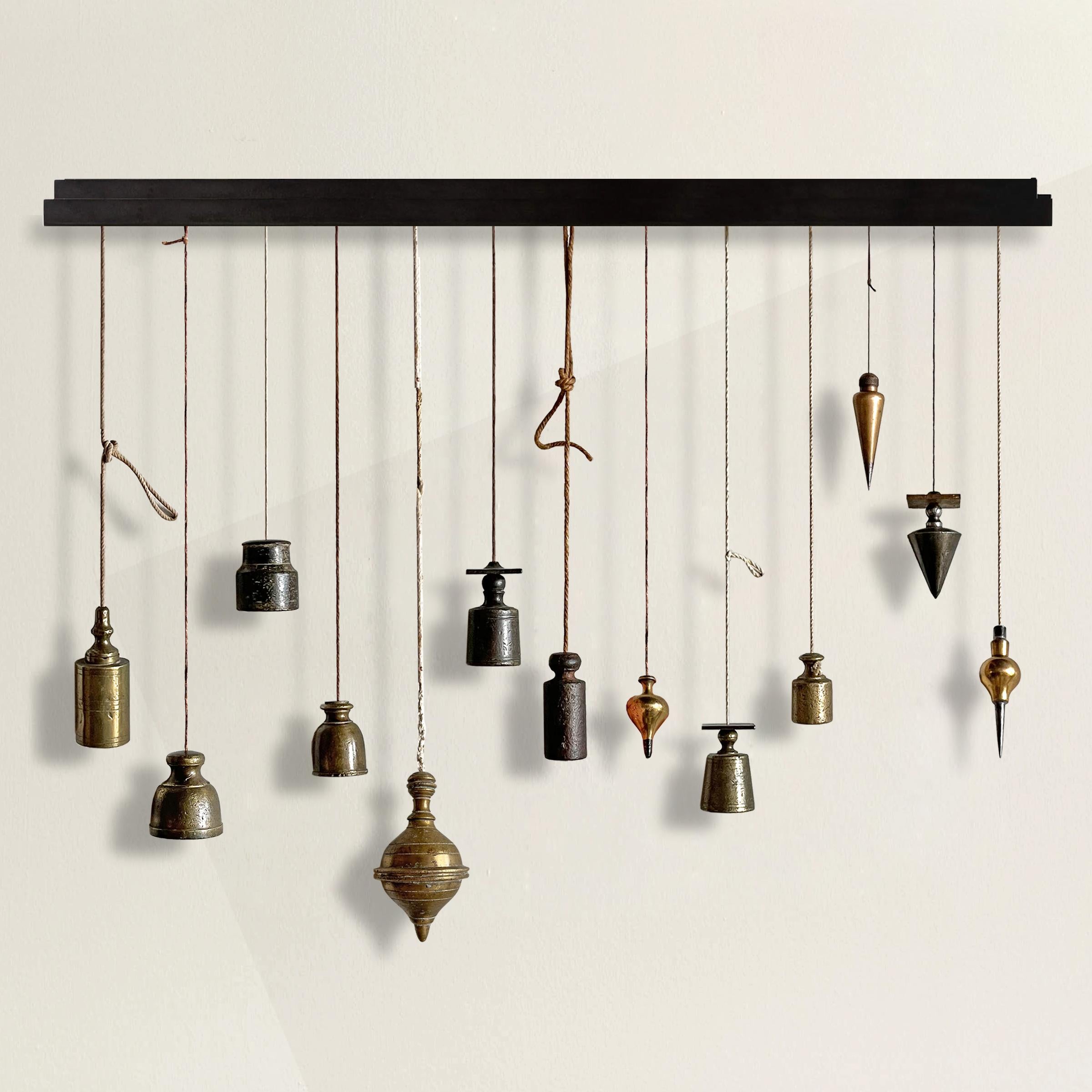 A chic and rare collection of thirteen 18th and 19th century French bronze and iron stone mason's plumb bobs hanging from a custom steel wall bracket. Can be arranged into any configuration desired. Found in various parts of France including