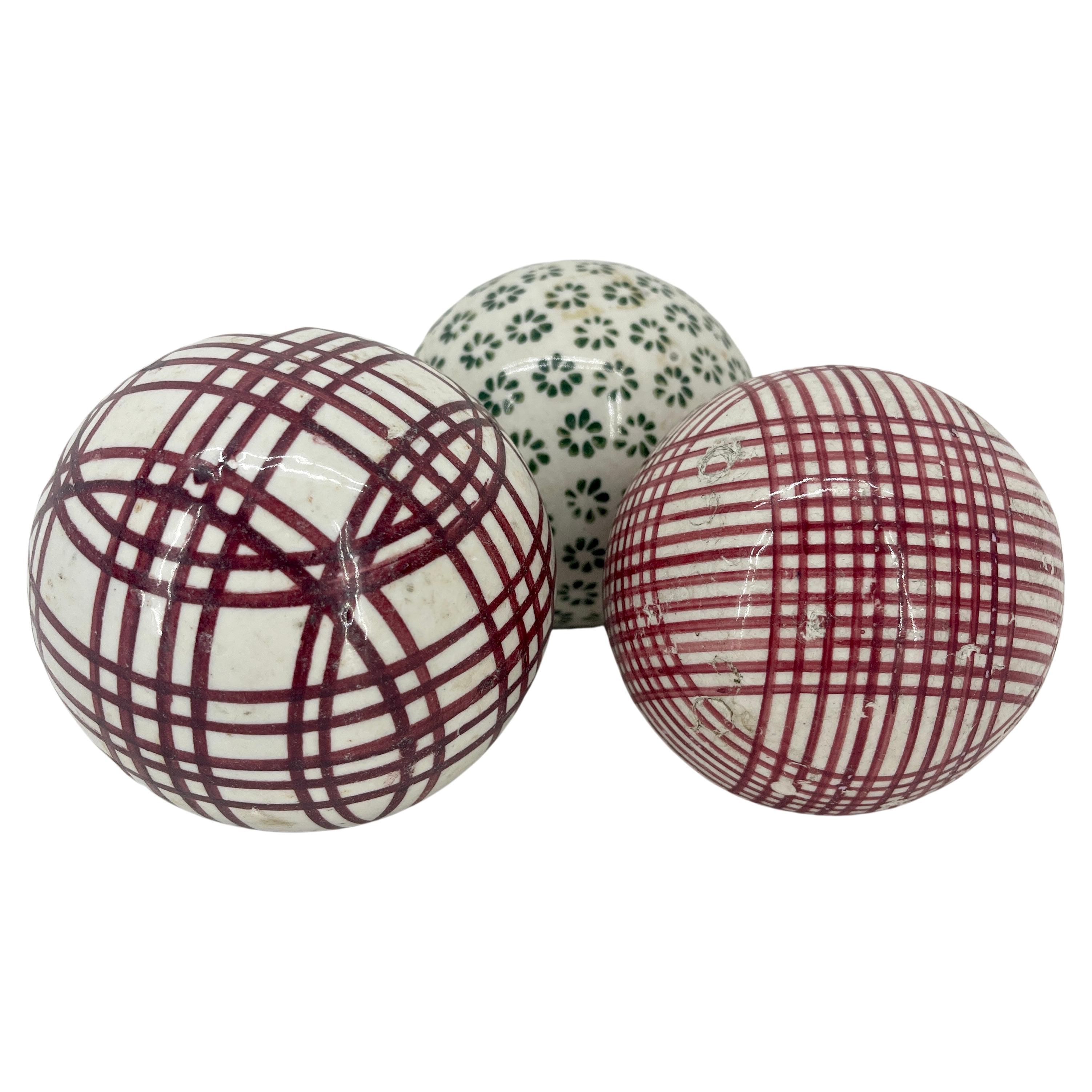 Set of three scottish stoneware carpet rug balls.

Carpet balls in reds and green. A storied game dating back Centuries, Carpet Ball is similar to Bocci Ball. An indoor game, a set of pins is set up in a hallway, and each player is given a set of