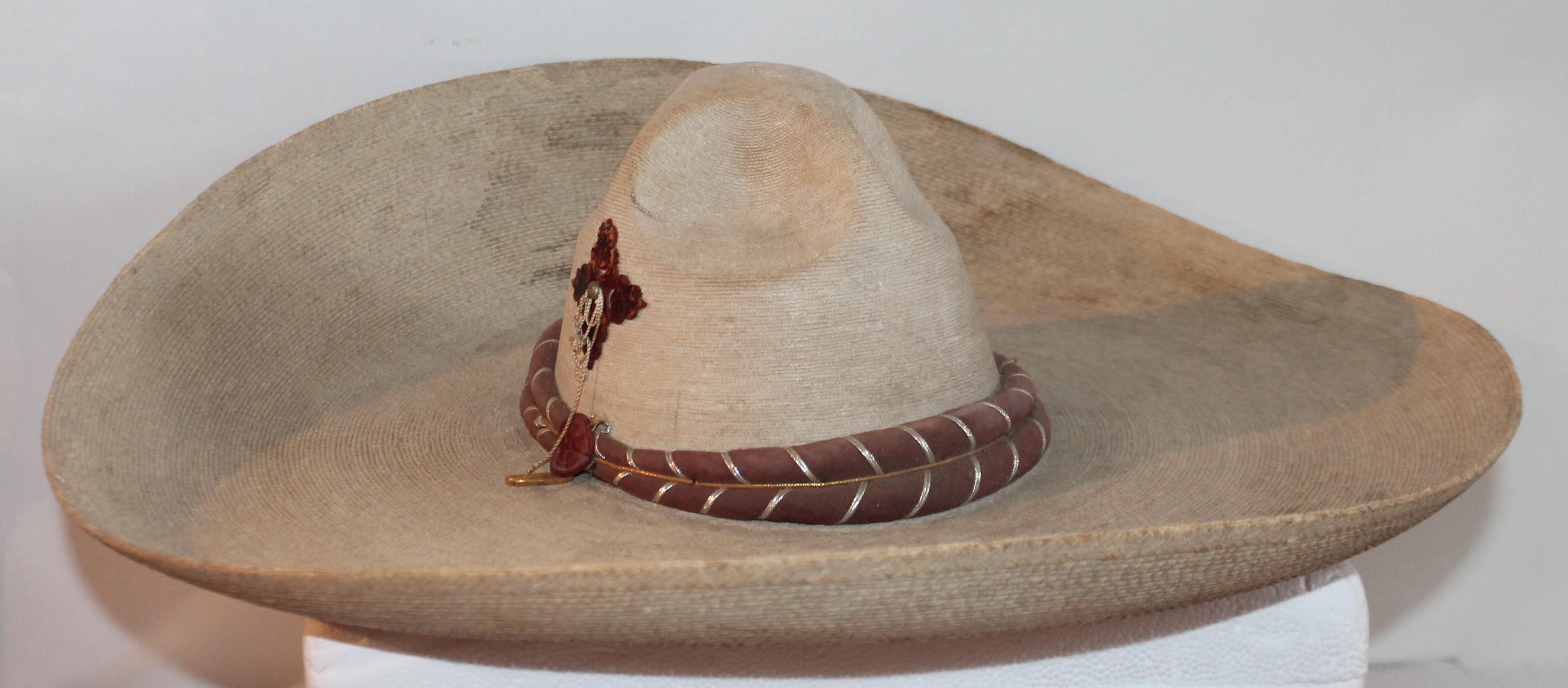 Collection of three handmade Mexican sombreros. In pristine condition with original label. Leather straps make the bans around the crown of two of the sombreros and the other has a beautiful handmade geometric pattern around the brim and the crown.