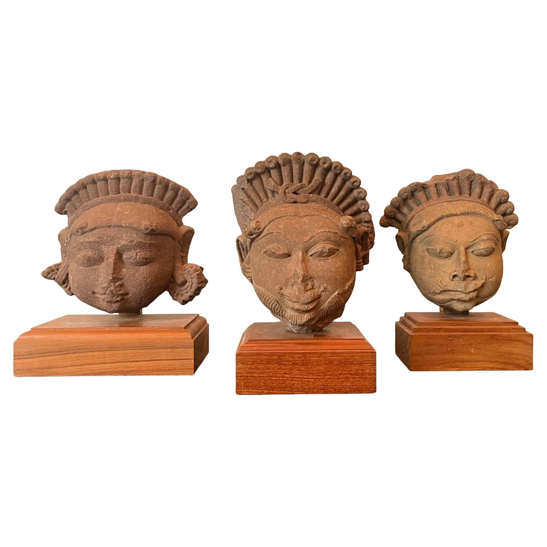 Kollektion von drei geschnitzten Köpfen von Gottheiten aus indischem Sandstein
