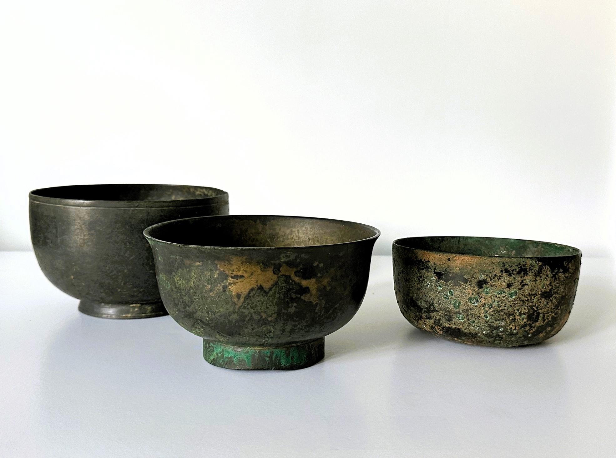 A collection of three bronze bowls from Korean dated to 14-17th century (late Goryeo to early Joseon Dynasty). It consists of an early example with a slight curvy wall and a high foot ring wiht fasten pins. The prototype is dated to 13-14th century