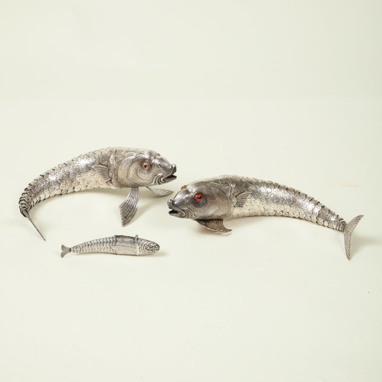 Comprising a larger pair of fish, perhaps stylized Koi, and a smaller fish; each with jeweled eyes and body realistically modeled with articulated sections allowing the body to move from side to side.

Provenance: From the Collection of Mario