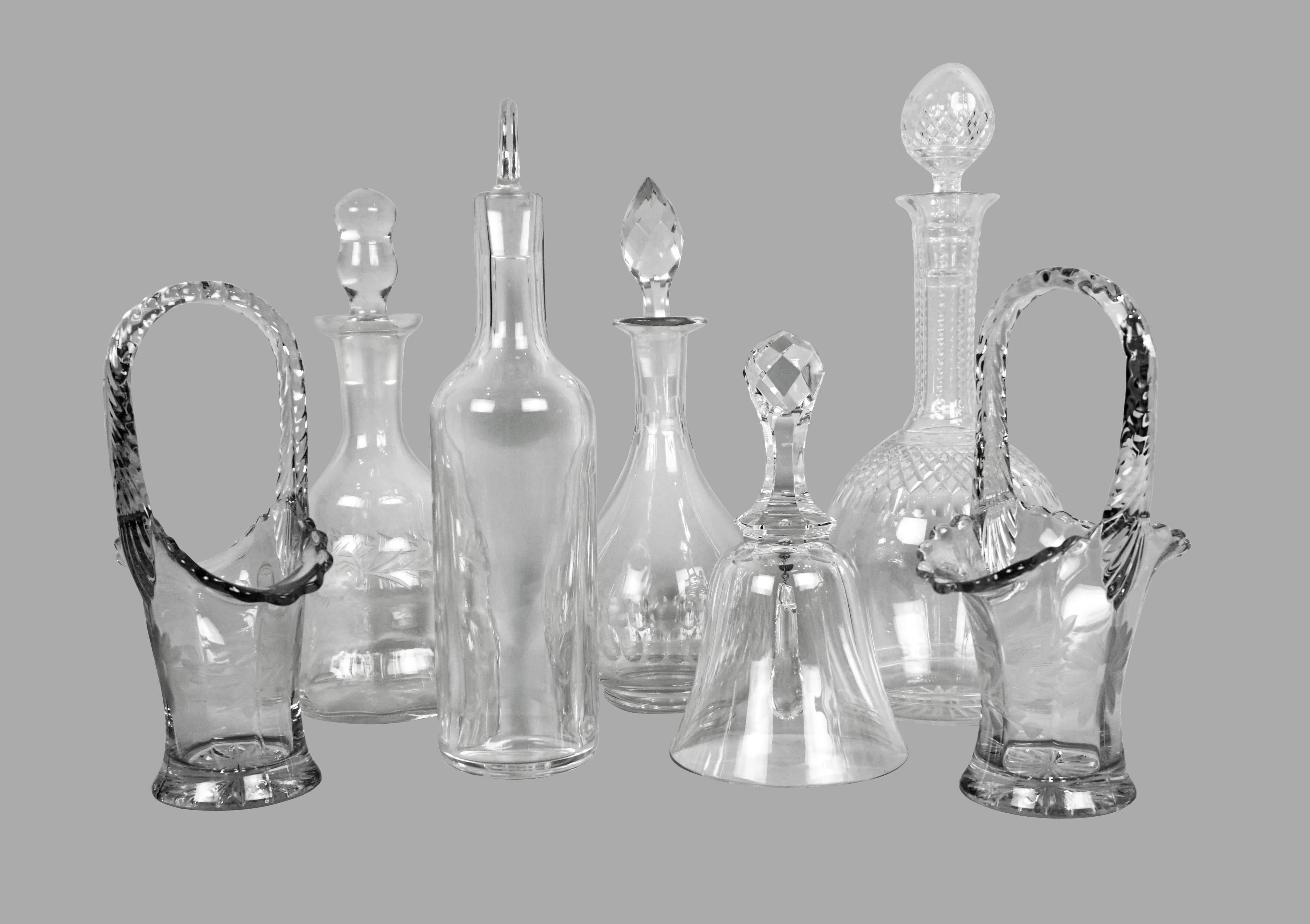 An interesting collection of vintage glass objects consisting of a pair of cut crystal candy dishes, four small decanters with stoppers including one signed Baccarat, and a glass dinner bell. All of the objects date from the first half of the 20th