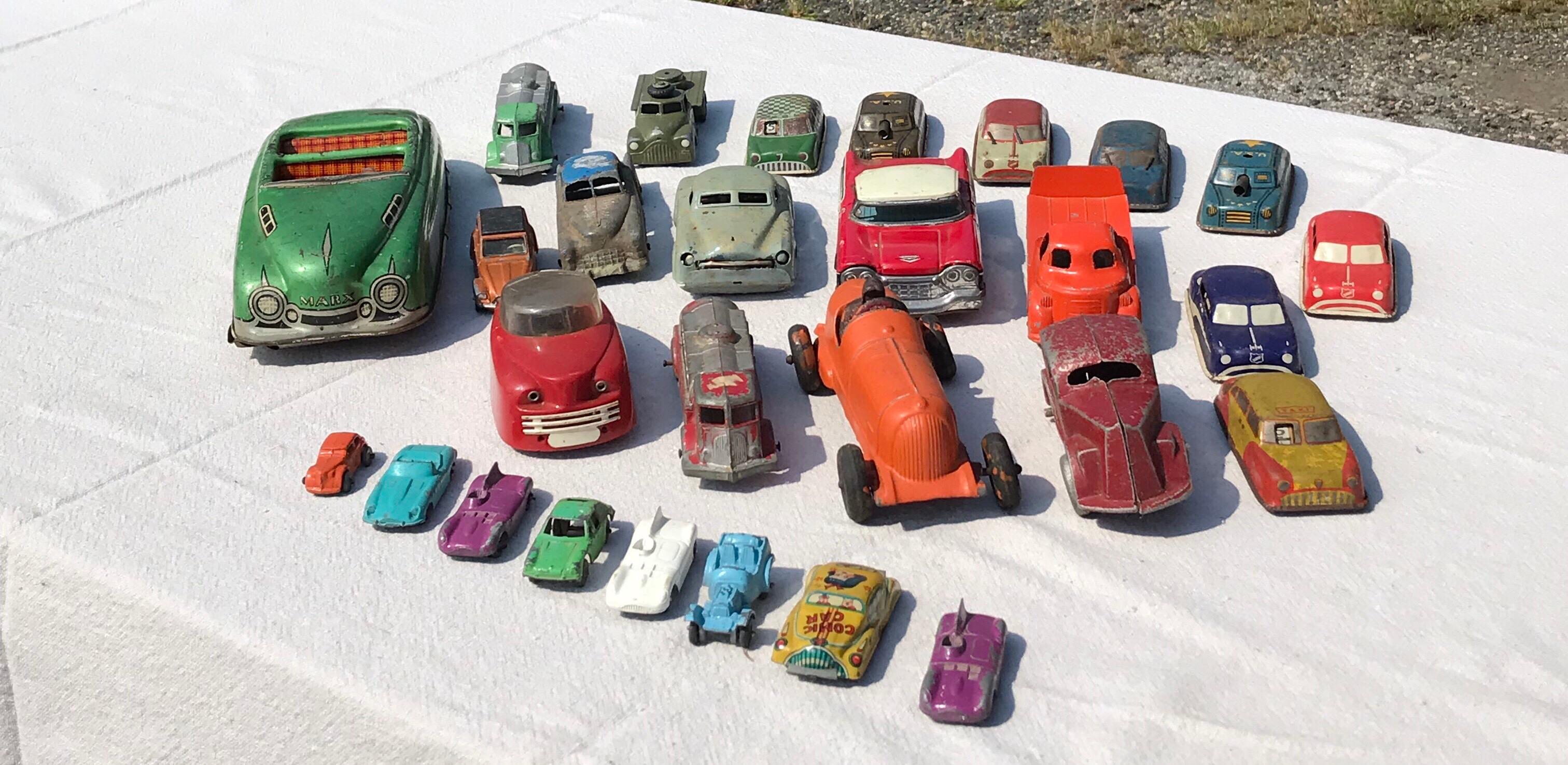 Collection of vintage toy cars. 28 total. It includes a large green tin litograph Friction Marx V89 toy convertible Car. An iron Hubley roadster in orange and a 1950s futuristic car in plastic. All push cars to play with that have rotating wheels.