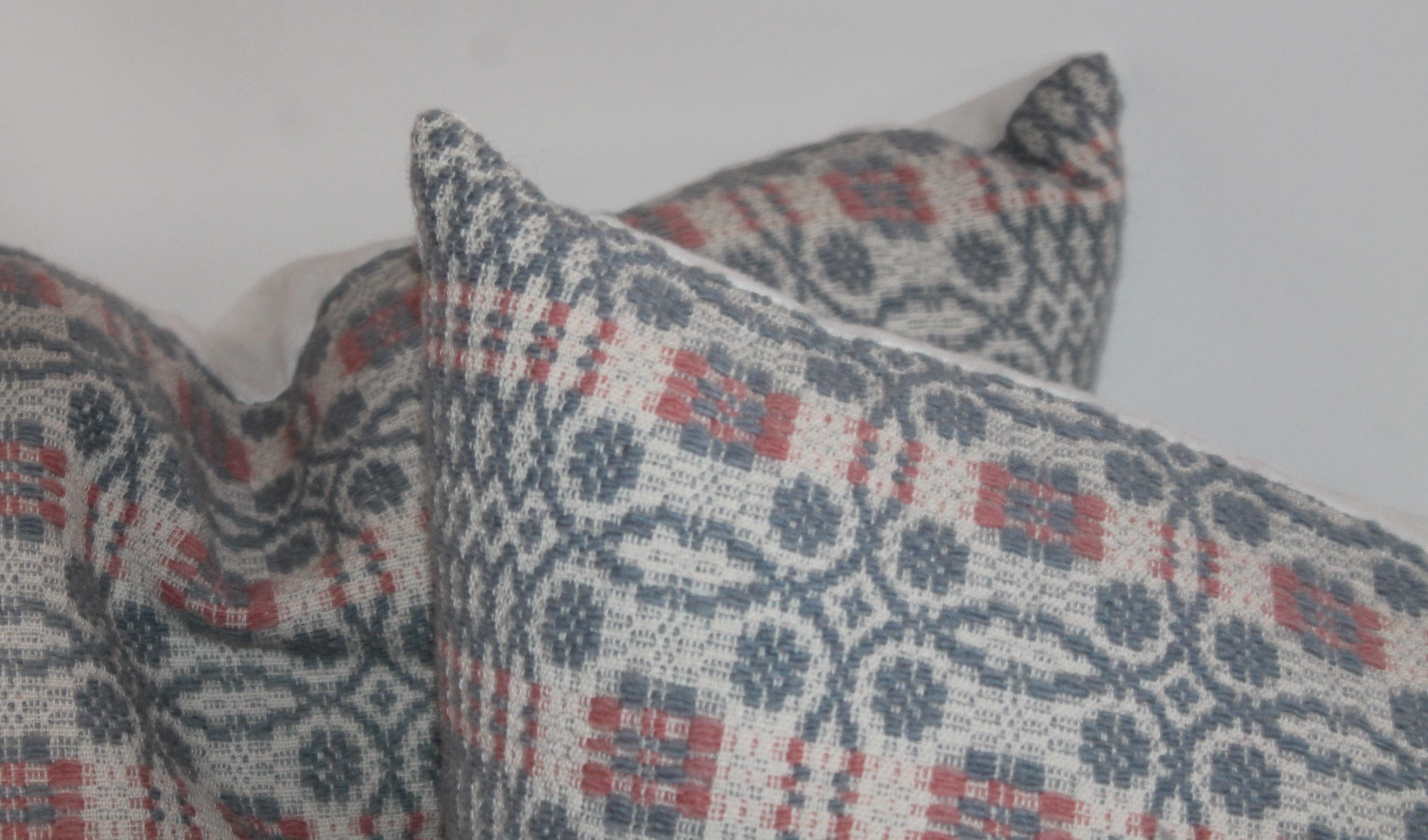 These fine hand woven coverlet pillows in blue grey with salmon trim. The backings are in homespun cotton linen. Sold as a group of four.