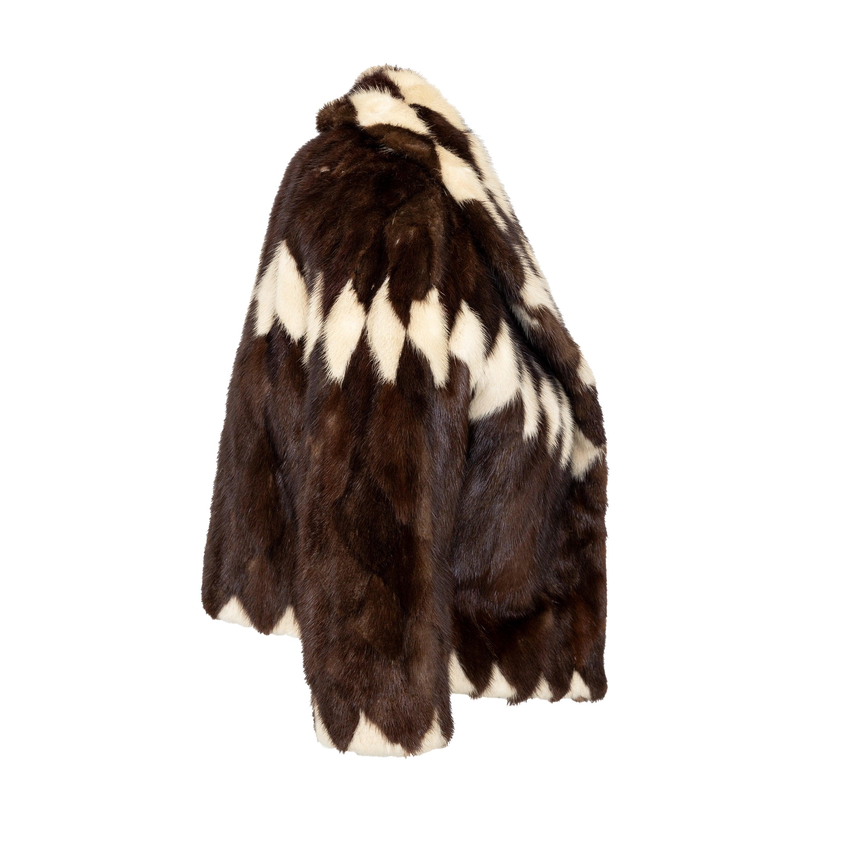 This vintage Collection Priveé fur coat from the 60s features a chic short jacket design crafted in luxurious mink fur. The striking harlequin diamond pattern is printed in rich tones, with contrasting off-white accents. The coat is finished with