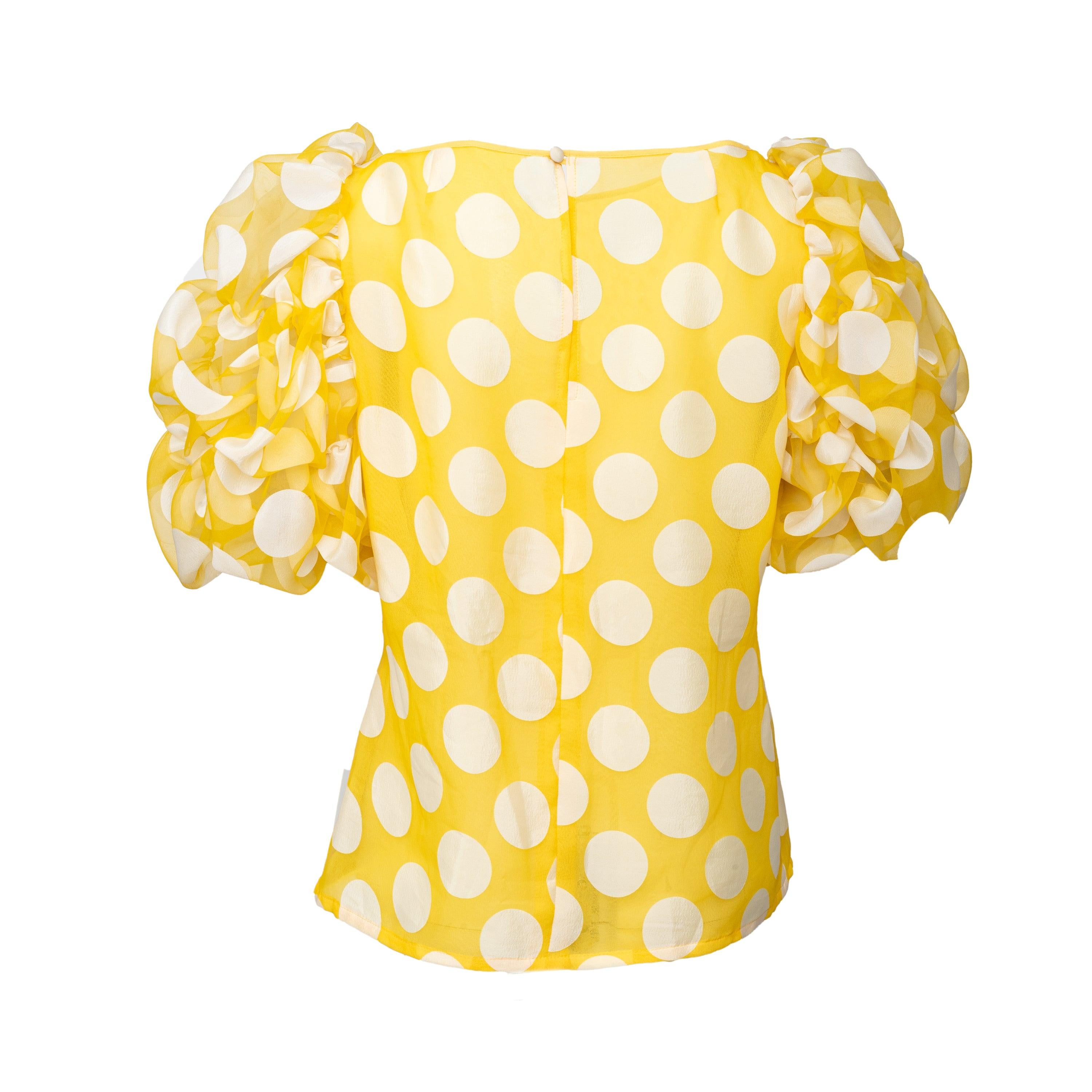 Questo top giallo a pois è realizzato in misto viscosa e poliestere, un tessuto morbido e resistente. Lo scollo a barchetta e le maniche a sbuffo aggiungono un tocco di femminilità, mentre il tessuto semitrasparente è foderato per un abbigliamento
