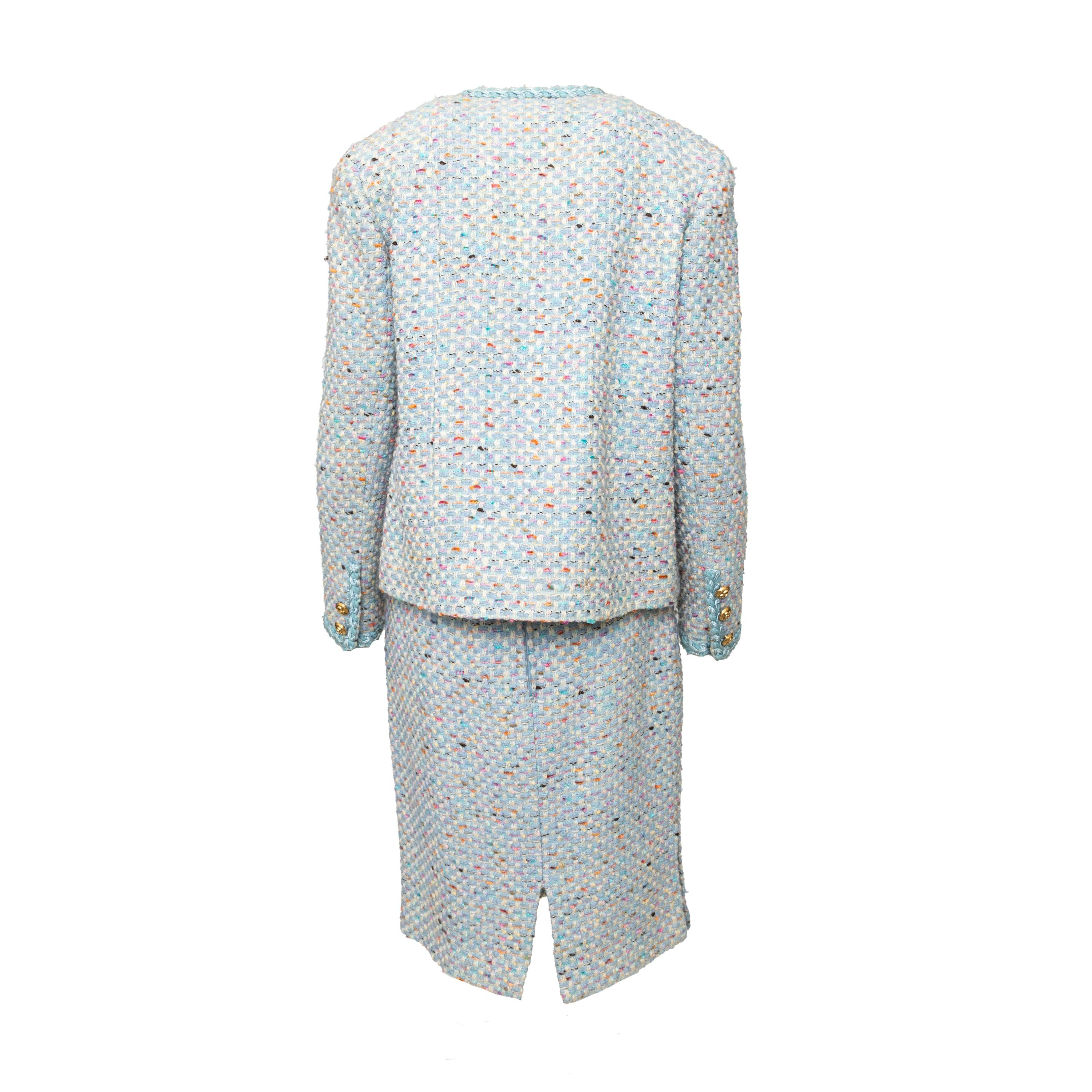 Questo set in tweed di Collection Privée in morbido blu baby con accenti multicolore è caratterizzato da una giacca aperta sul davanti con finiture a treccia, bottoni dorati e una gonna di lunghezza midi.
 Osservazioni: Ci sono alcuni buchi nella