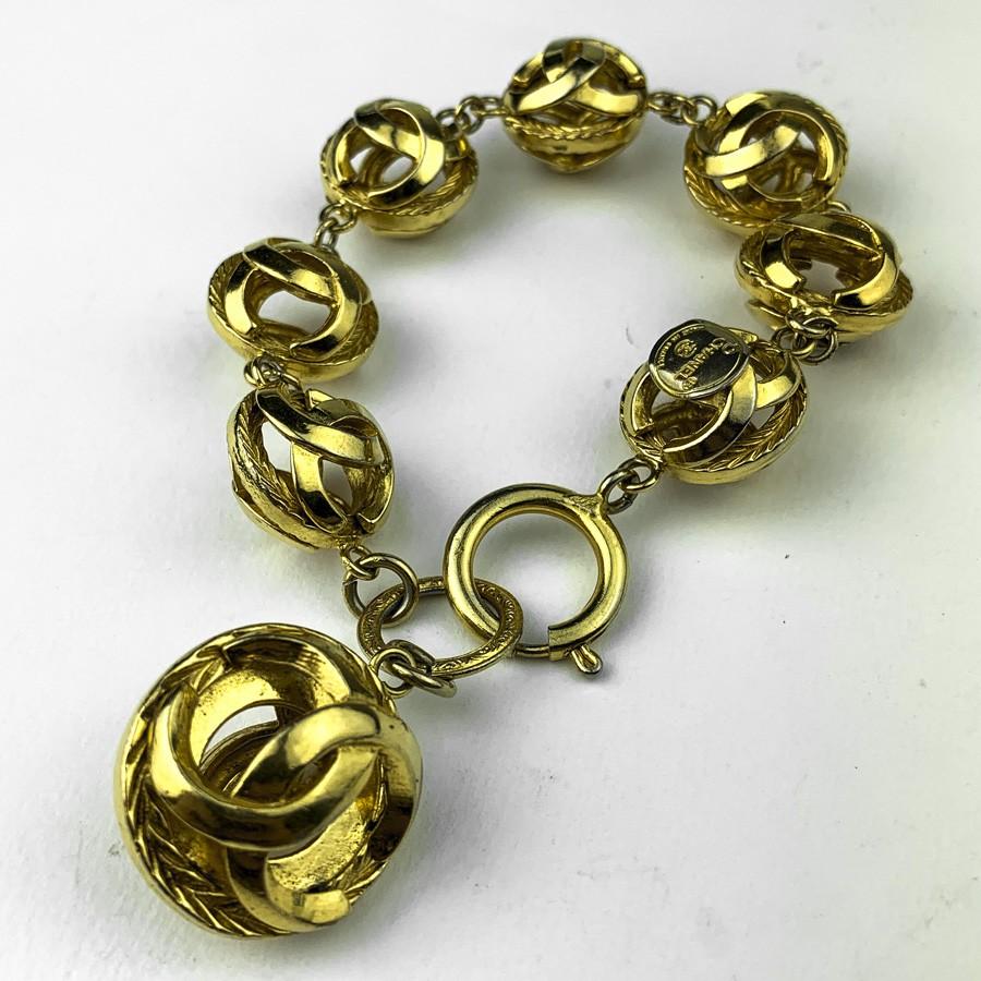 COLLECTOR, CHANEL vintage chain Bracelet in gilt metal. 
It represents a garland of 7 small CC balls which follow one another (each 2cm in diameter) and it ends with another larger sphere (3cm in diameter).
In very good condition.
Dimensions : It