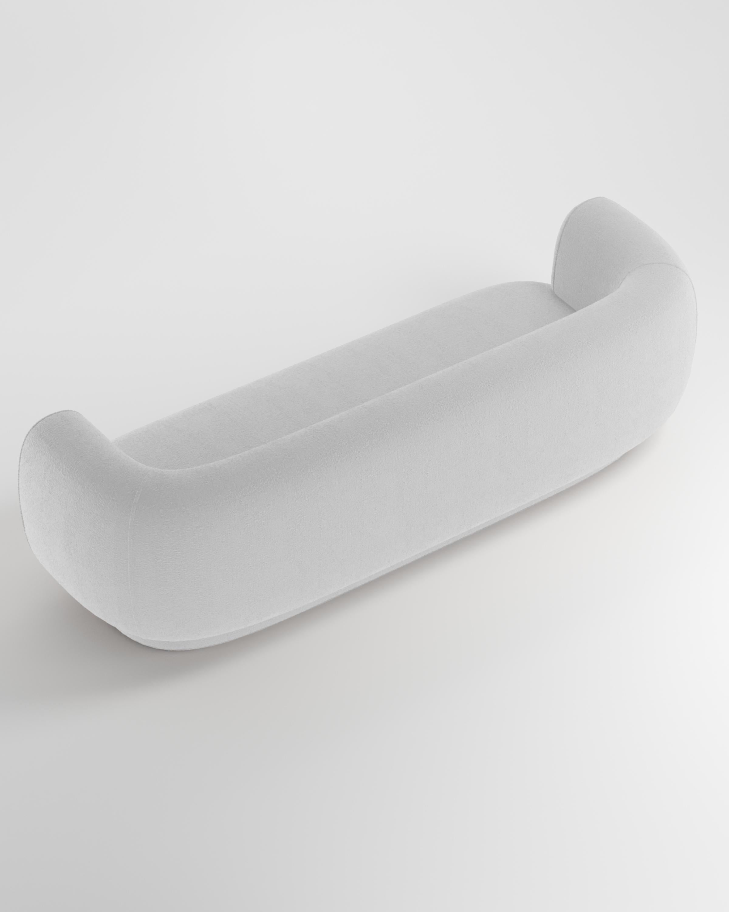 Le canapé Hug se caractérise par des lignes simples et épurées et un accoudoir distinctif.
L'accoudoir, qui chevauche à moitié le coussin d'assise, crée un détail d'emboîtement entre les deux éléments, tandis que le padding, ferme et accueillant à